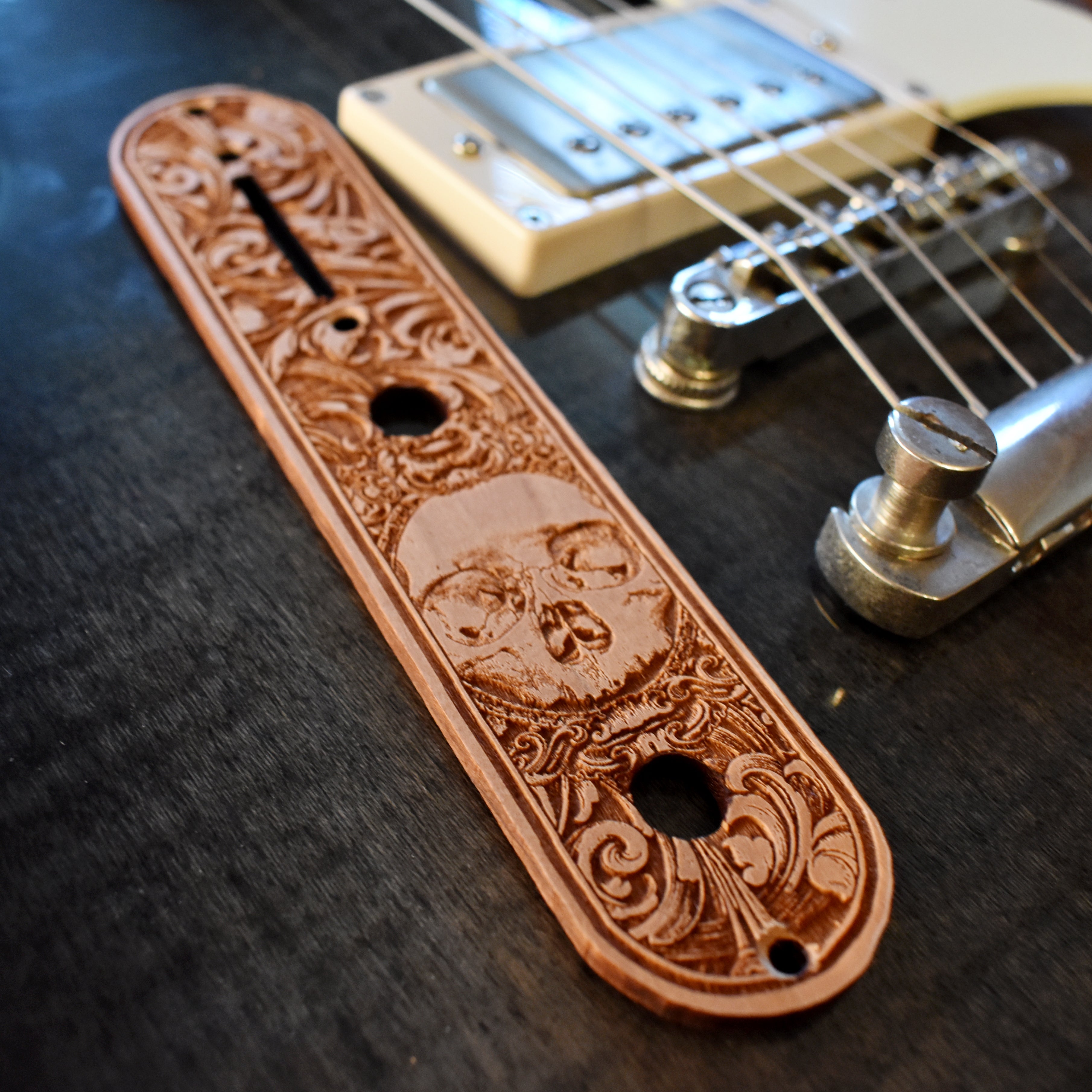 Custom engraved skull design on wood, ideal for guitar truss rod covers or decorative art, detailed craftsmanship with dark shading and intricate features.