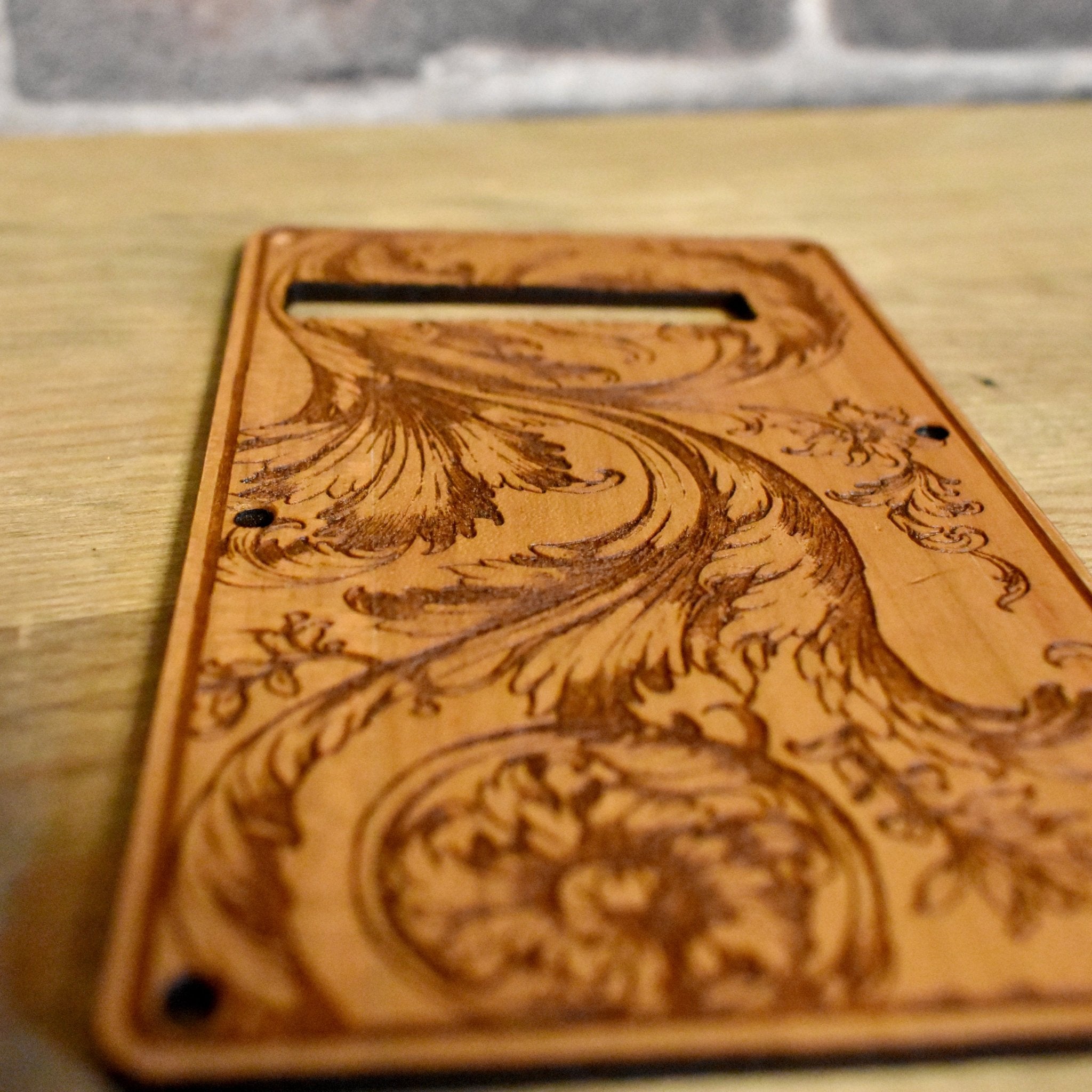 Strato-style electric guitar tremolo cover with intricate floral engraving