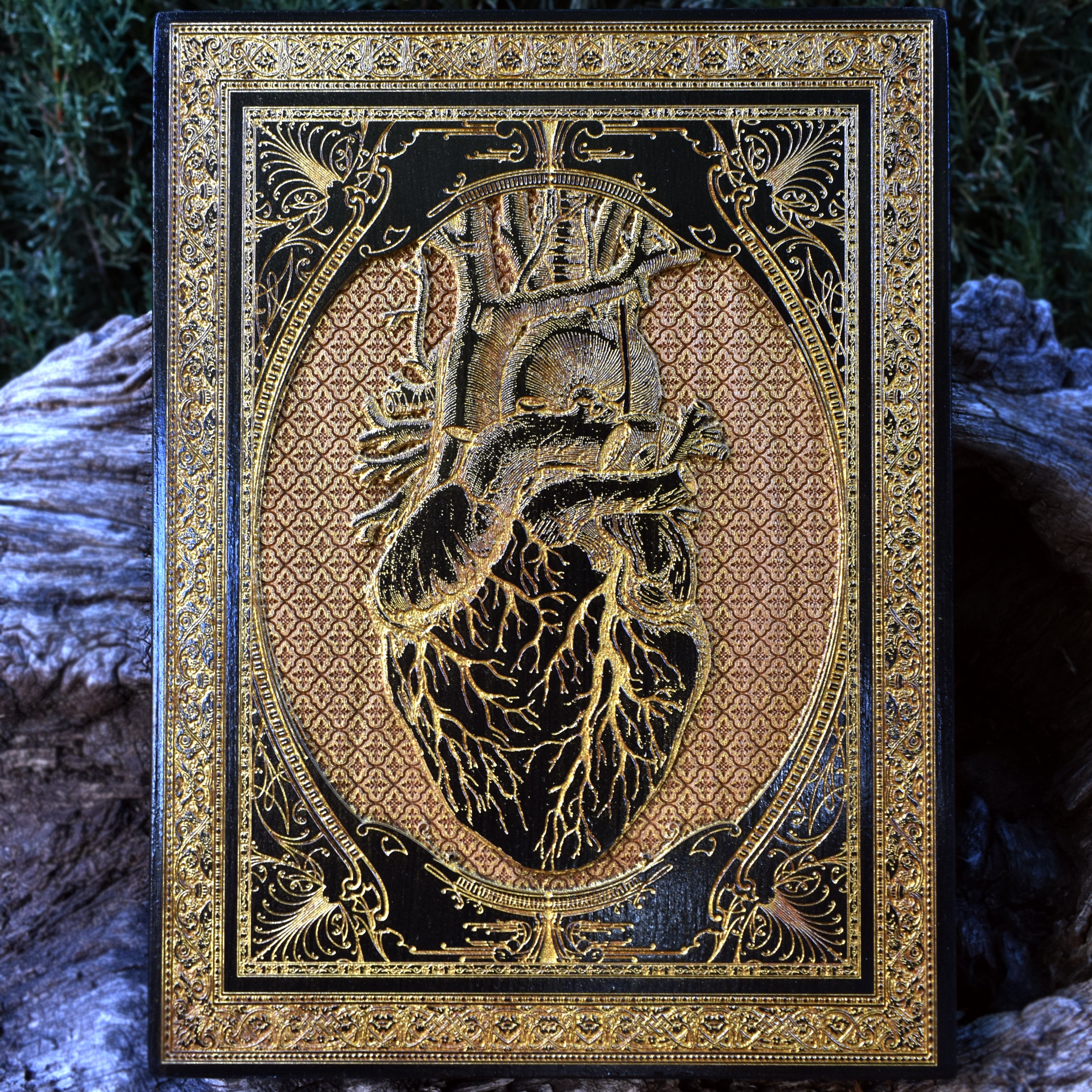Anatomical heart art on wood with black paint and gold filling, gothic heart design.