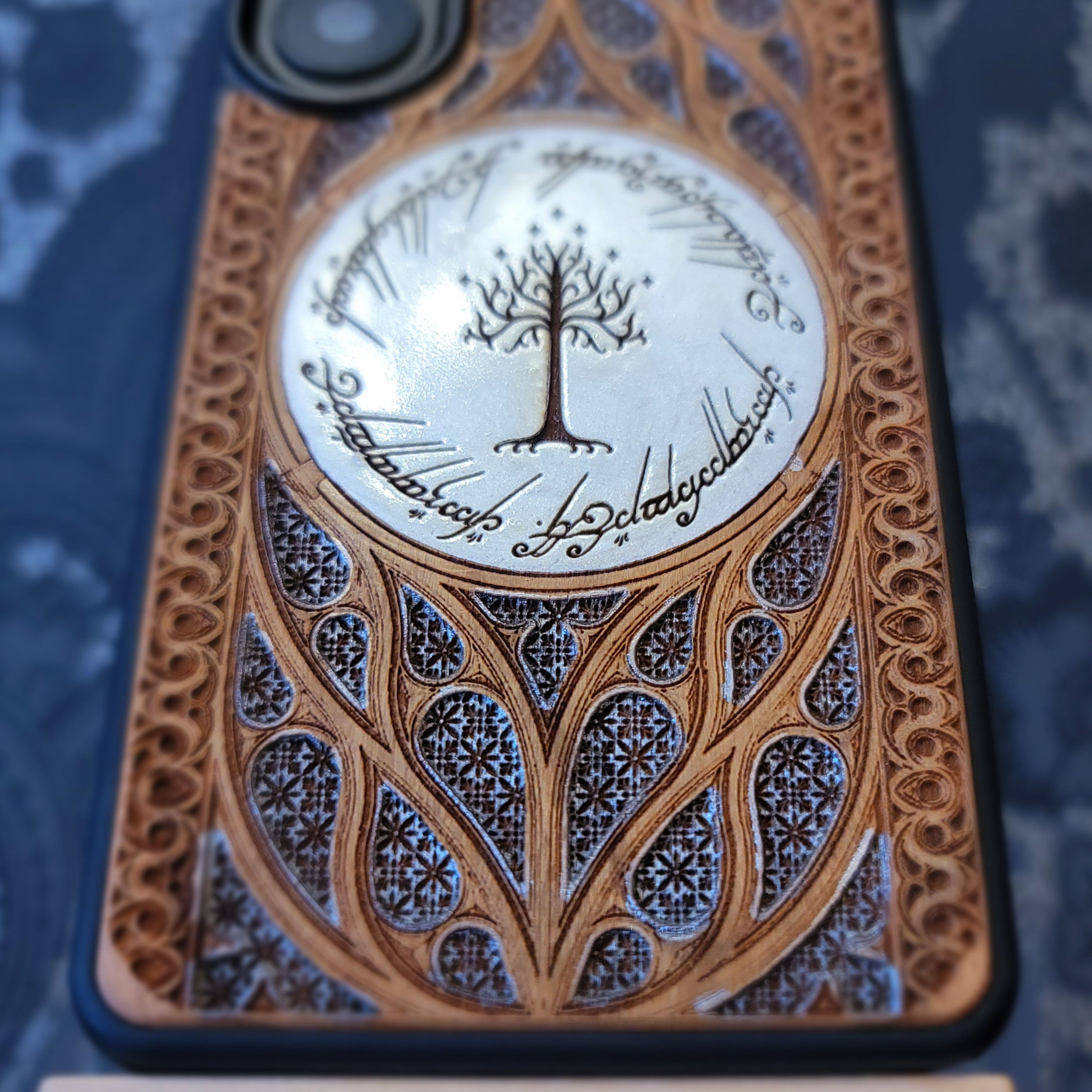 Phone case with intricate design and tree of Gondor emblem on a grey background