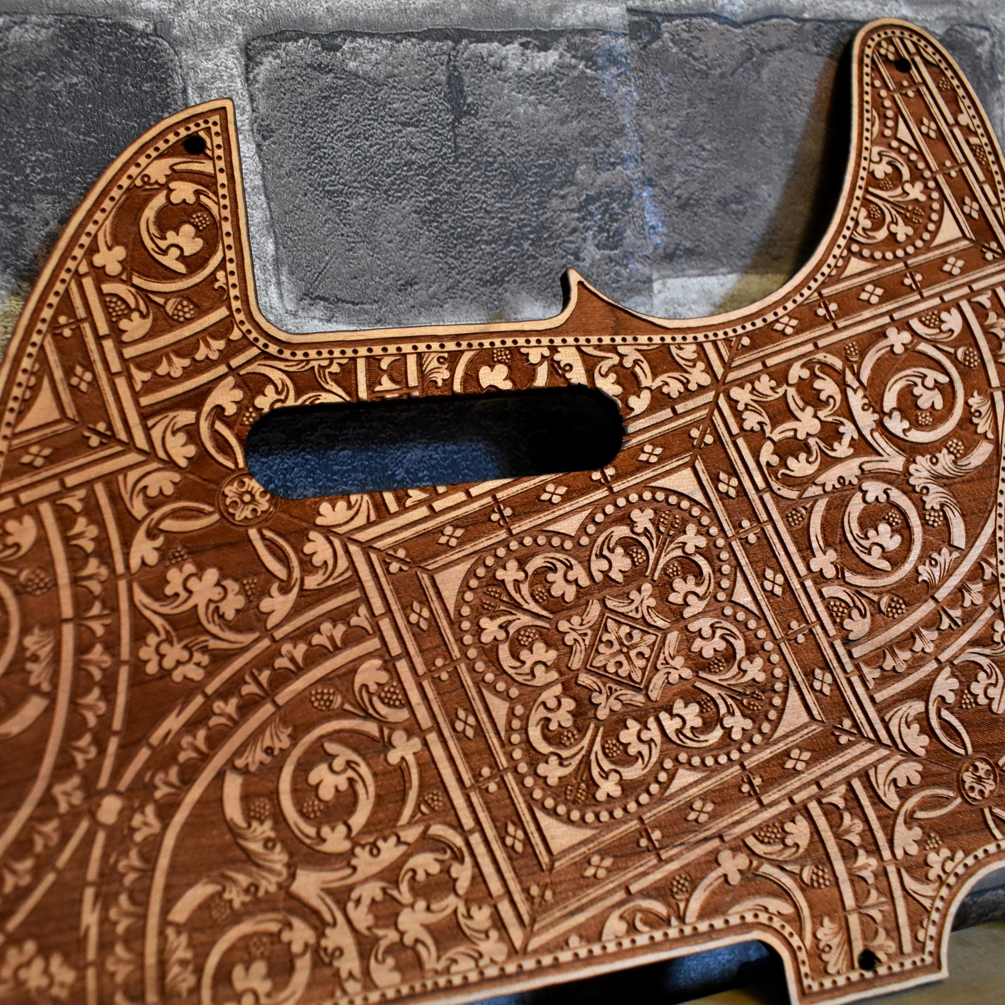 Close-up of laser-engraved cherry wood pickguard for Fender Telecaster