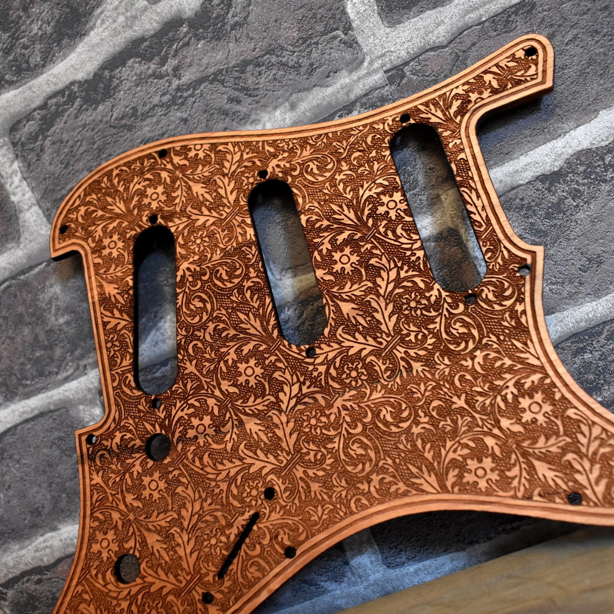 Close-up of laser-engraved Aztec pattern on cherry wood pickguard for Fender Stratocaster