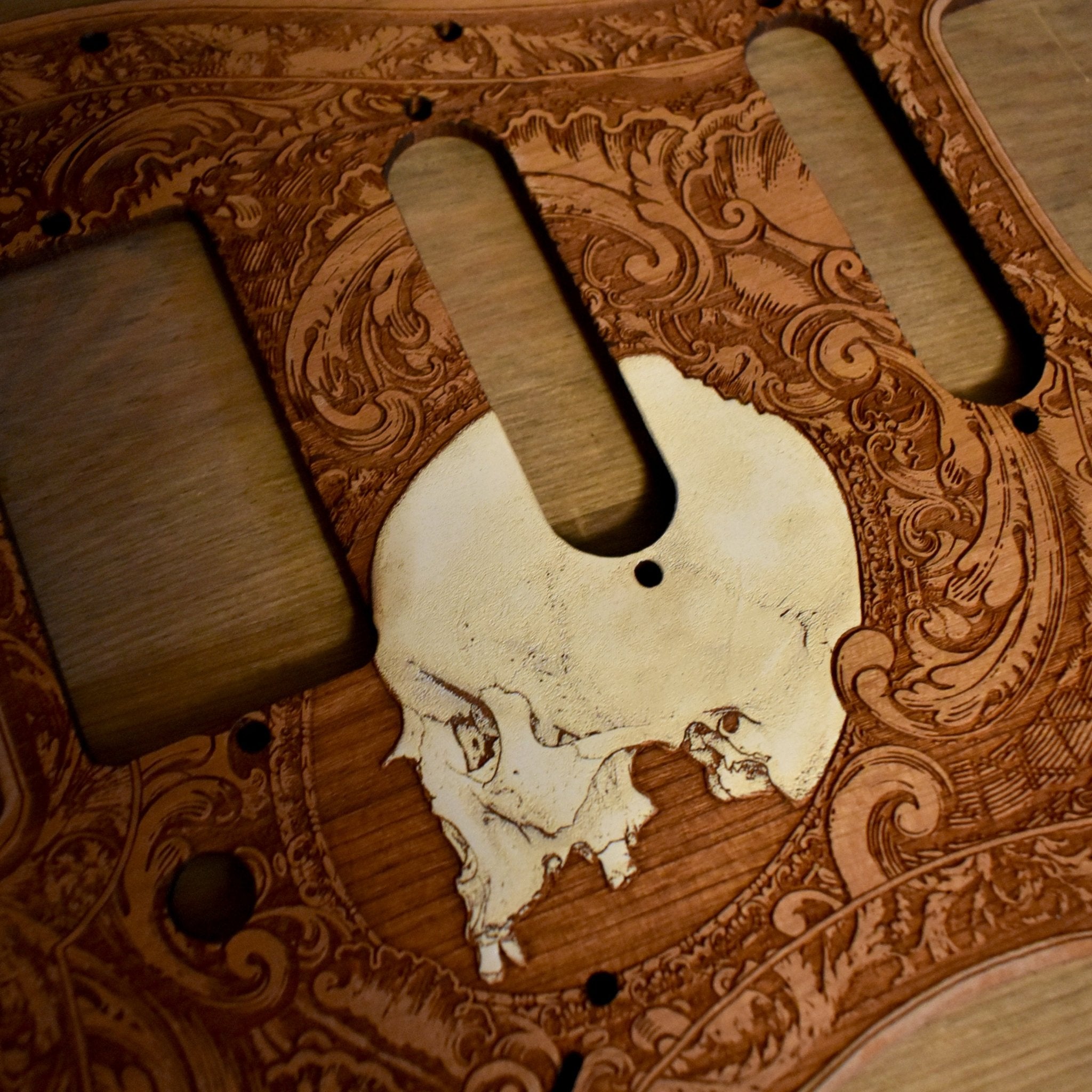Custom cherry wood pickguard with skull engraving for Fender Stratocaster guitars.