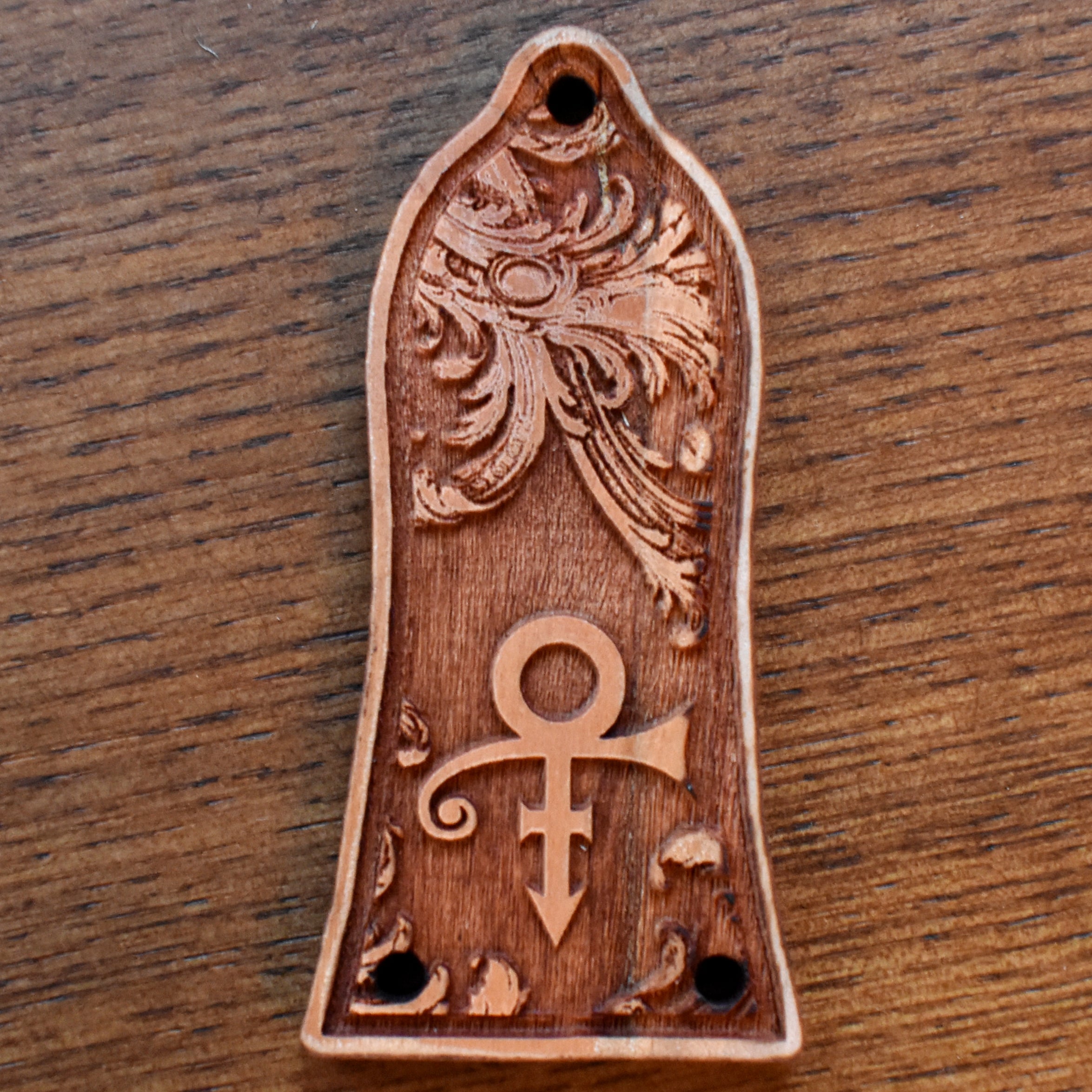 Engraved cherrywood truss rod cover for Epiphone guitar, featuring Prince inspired symbol design, handcrafted by Engraverβs Dungeon.