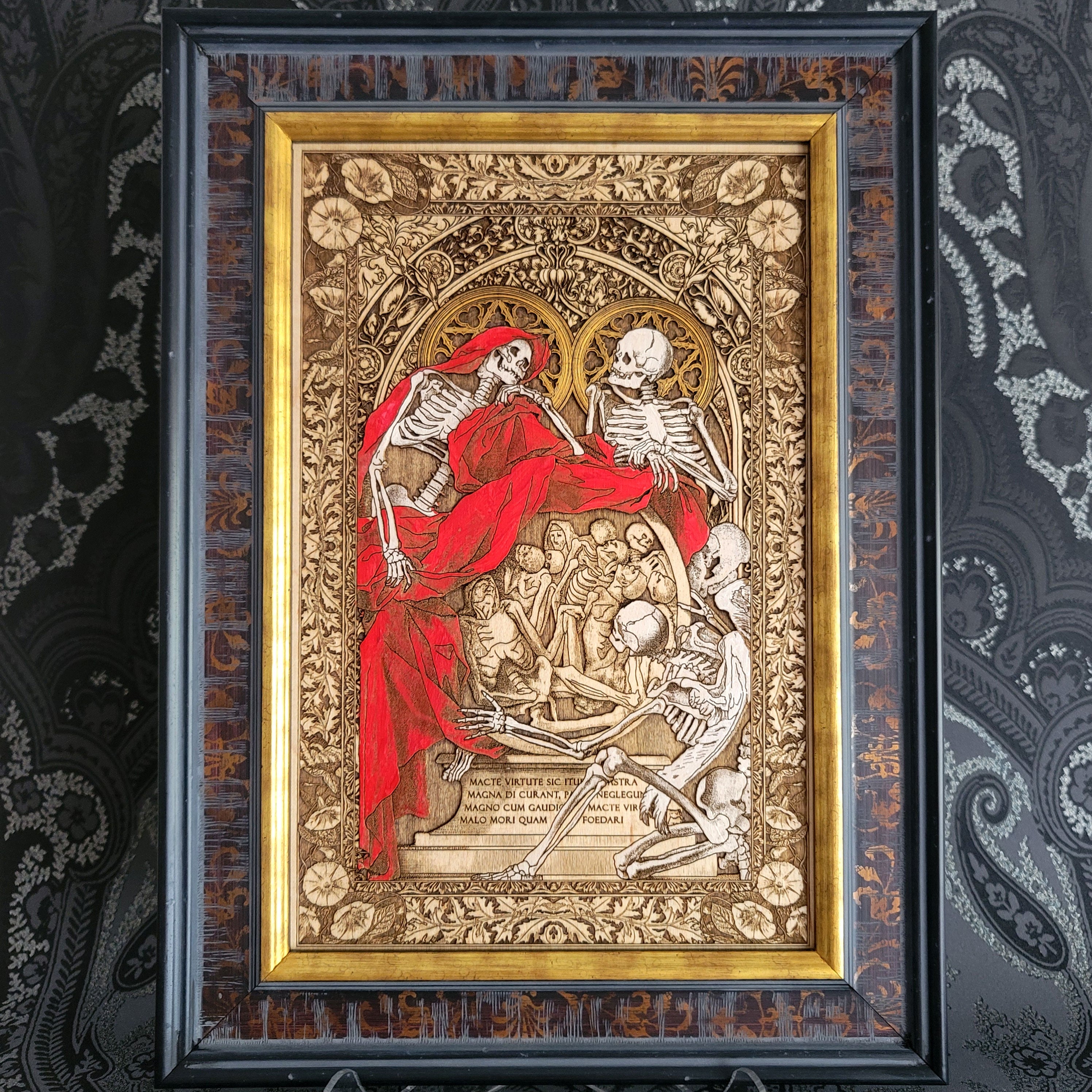 Decorative artwork with skeletons and red fabric in a ornate frame on a patterned background