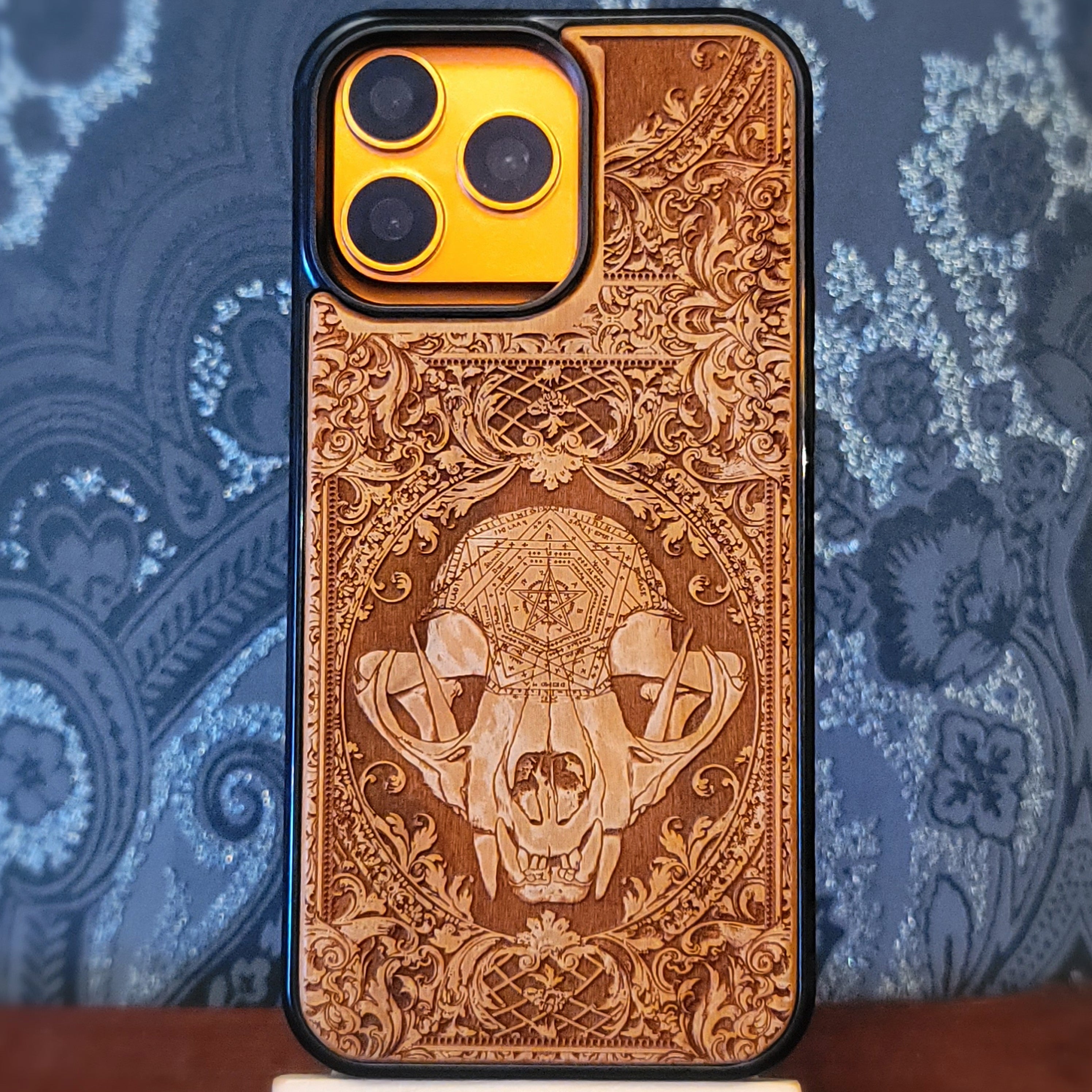 Deep laser engraved wooden phone case featuring a mystical cat skull design with witchy dark art details on natural wood for iPhone and Samsung Galaxy models.
