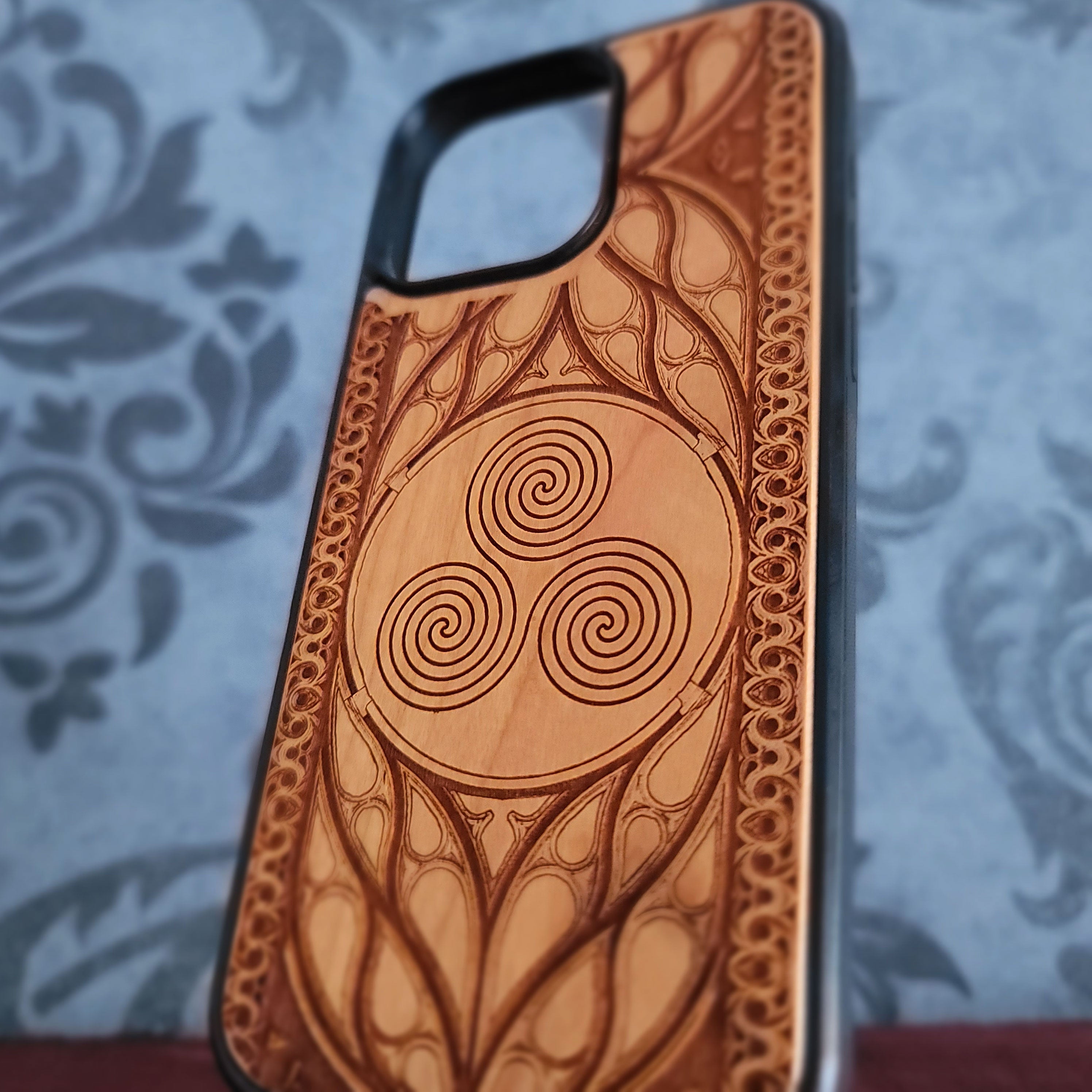 Celtic Spiral engraved wood phone case for iPhone and Galaxy with triskelion symbol in gothic wood frame.