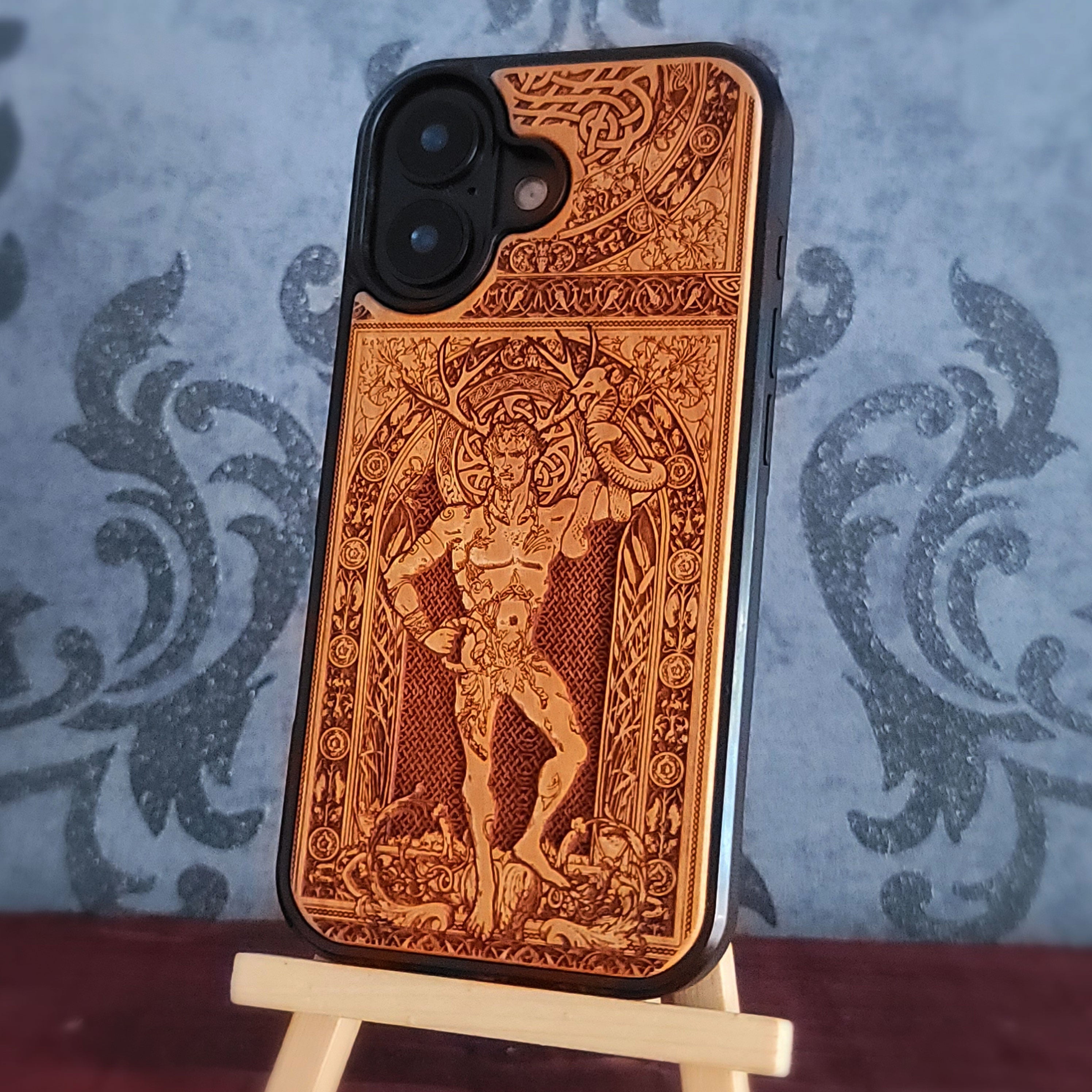 A wooden phone case with an intricate carved cernunnus figure