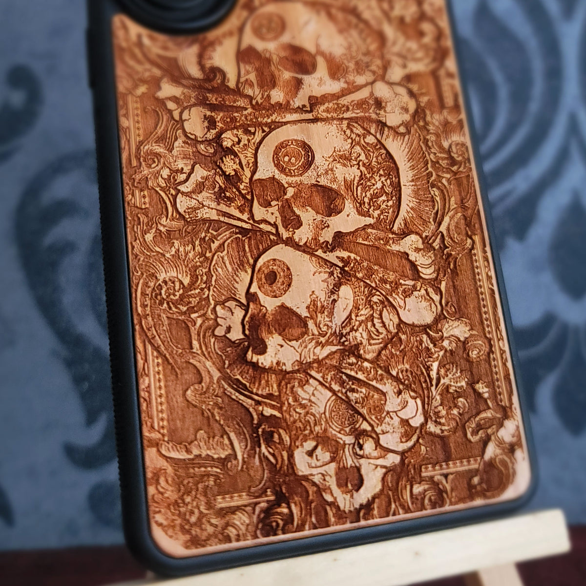Engraved wood phone case with stacked skull design and black protective bumper