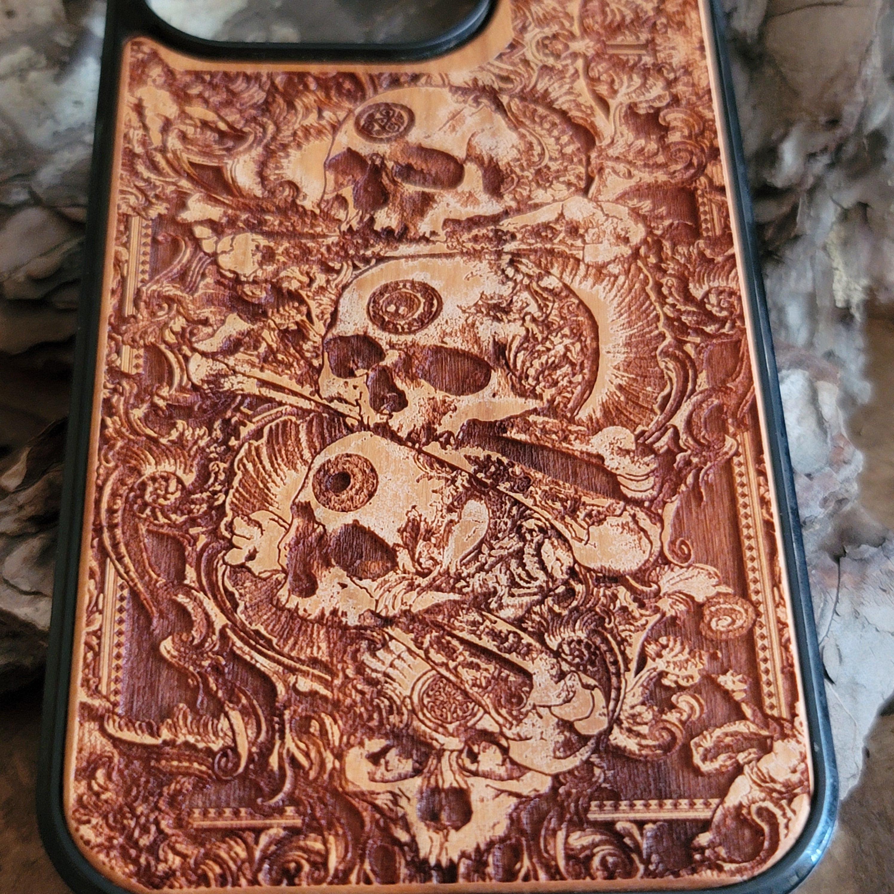 Handcrafted wooden phone case with detailed skull engravings inspired by medieval church architecture, compatible with iPhone , iPhone 15, iPhone 14, iPhone 13, iPhone 12, iPhone 11 Pro Max, iPhone 11 Mini, Samsung Galaxy S, S24, S23, S22, S21, S20 Ultra Plus, and Note 20.