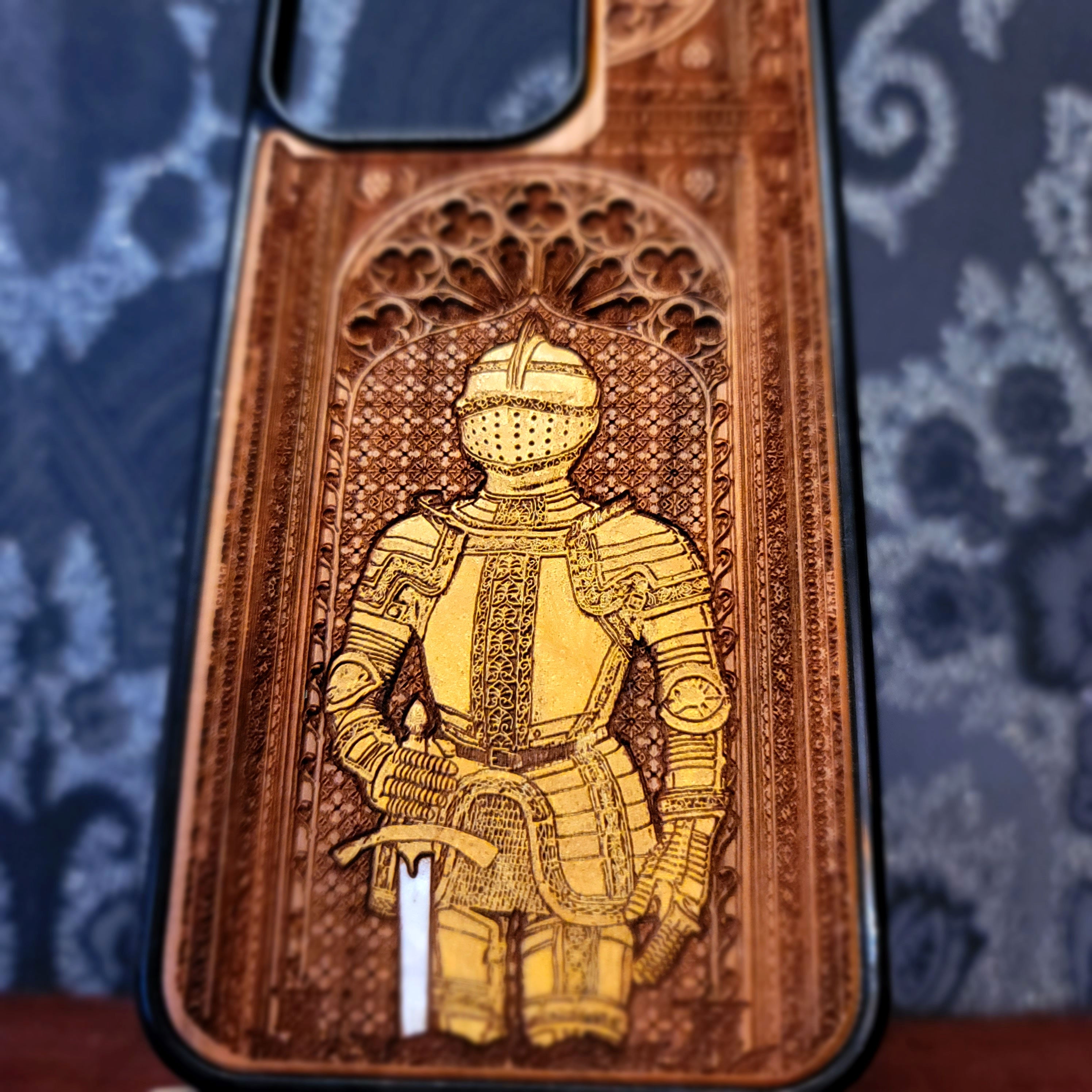 Deep laser engraved wooden phone case featuring a medieval knight in detailed armor holding a sword on natural wood for iPhone and Samsung Galaxy models.