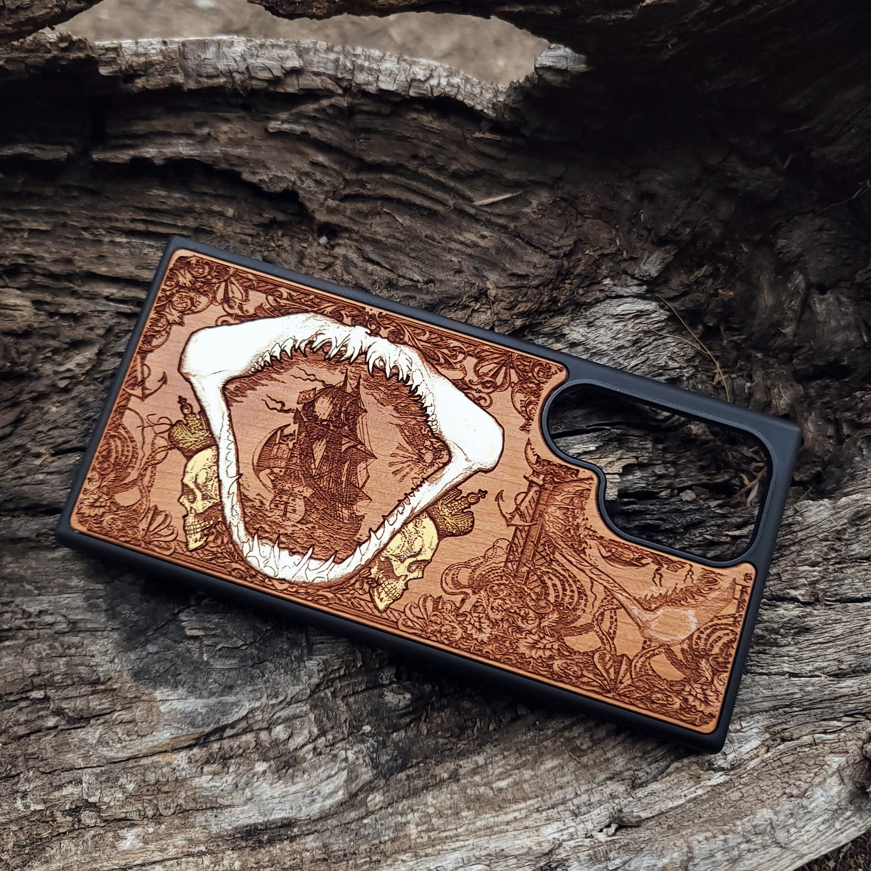 Close-up of handcrafted cherry wood phone case featuring a detailed shark engraving.
