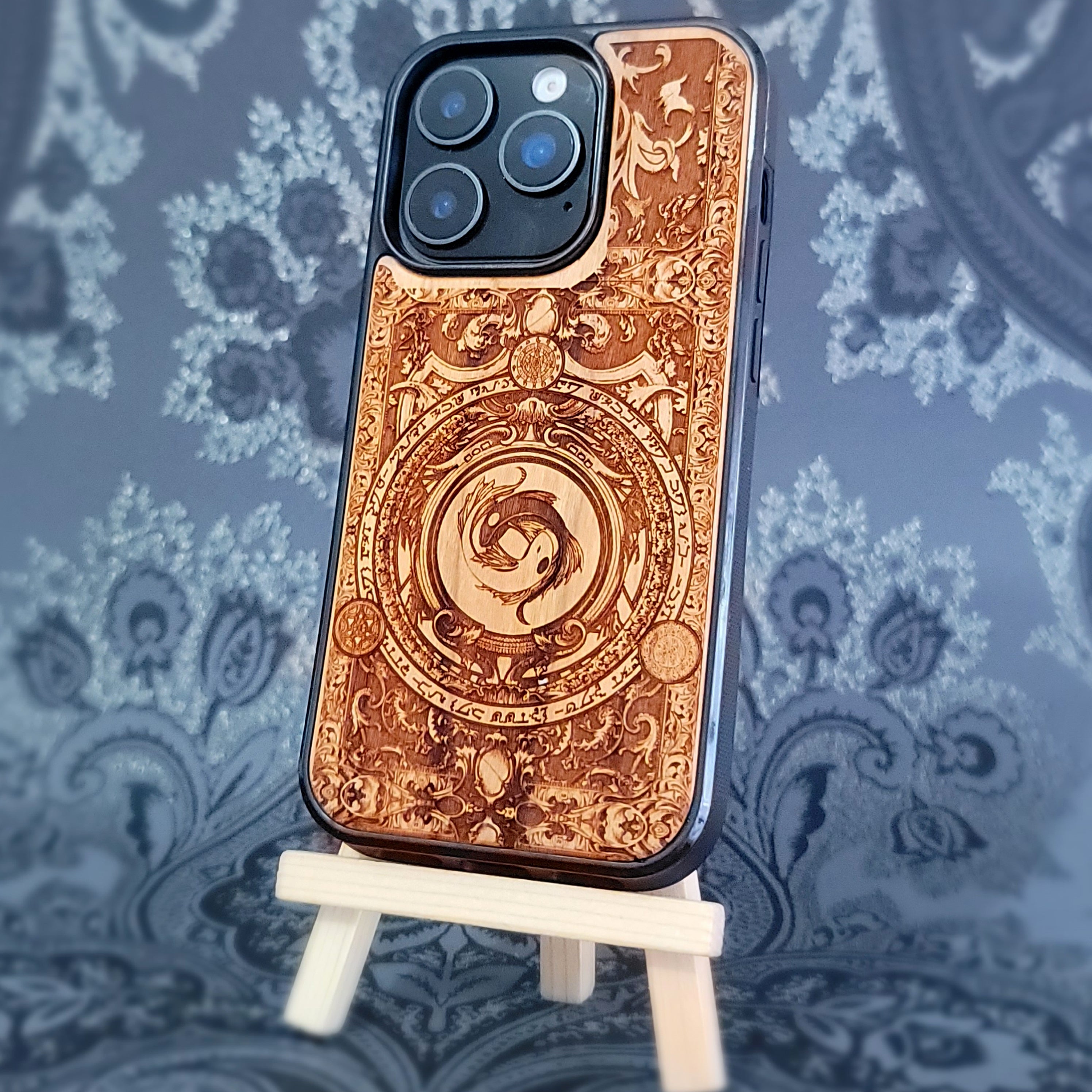 Deep laser engraved wooden phone case featuring two koi fish forming a yin yang symbol on natural wood for iPhone and Samsung Galaxy models.