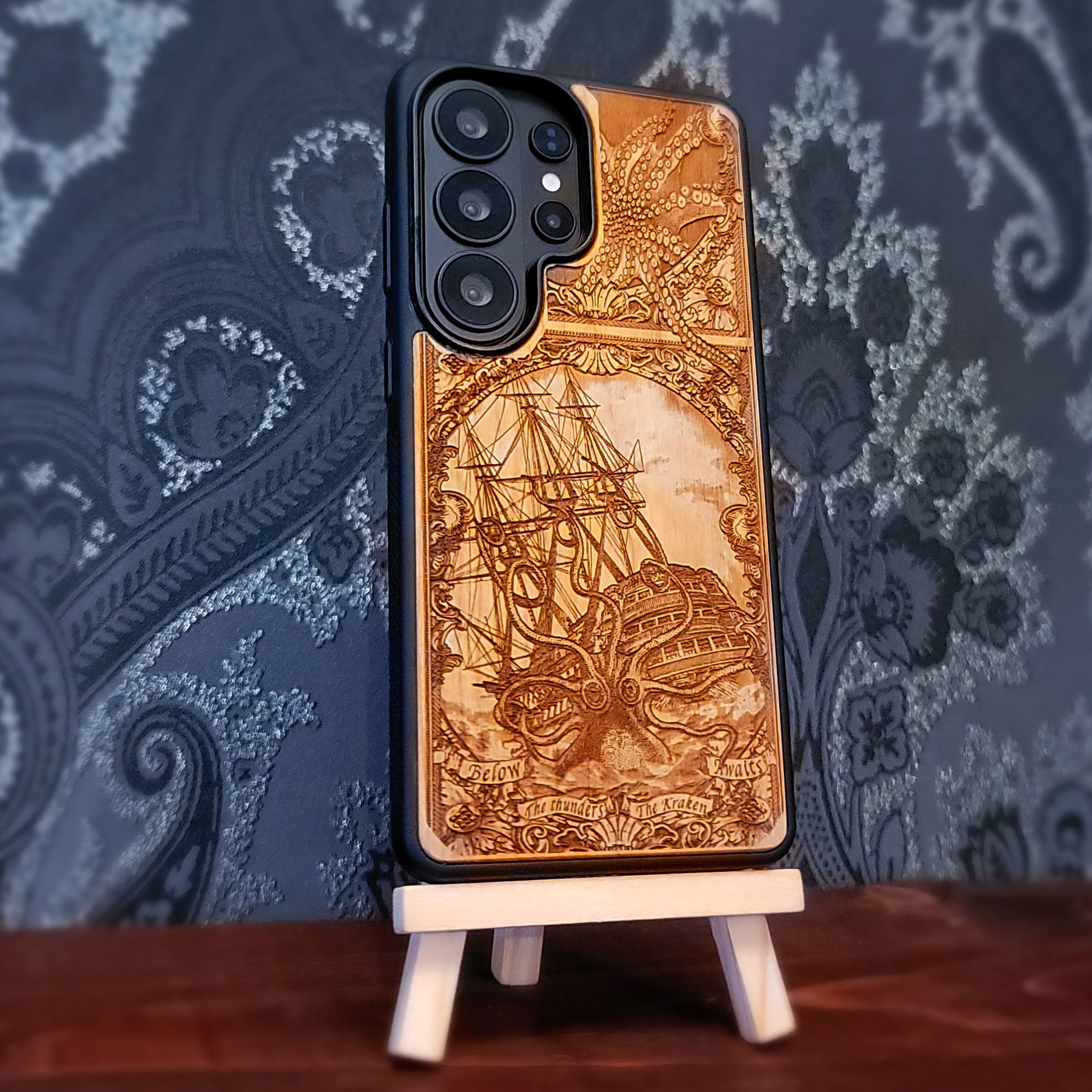 Laser engraved and hand painted wooden phone case featuring a giant Kraken sea monster attacking a ship for iPhone and Samsung Galaxy models.