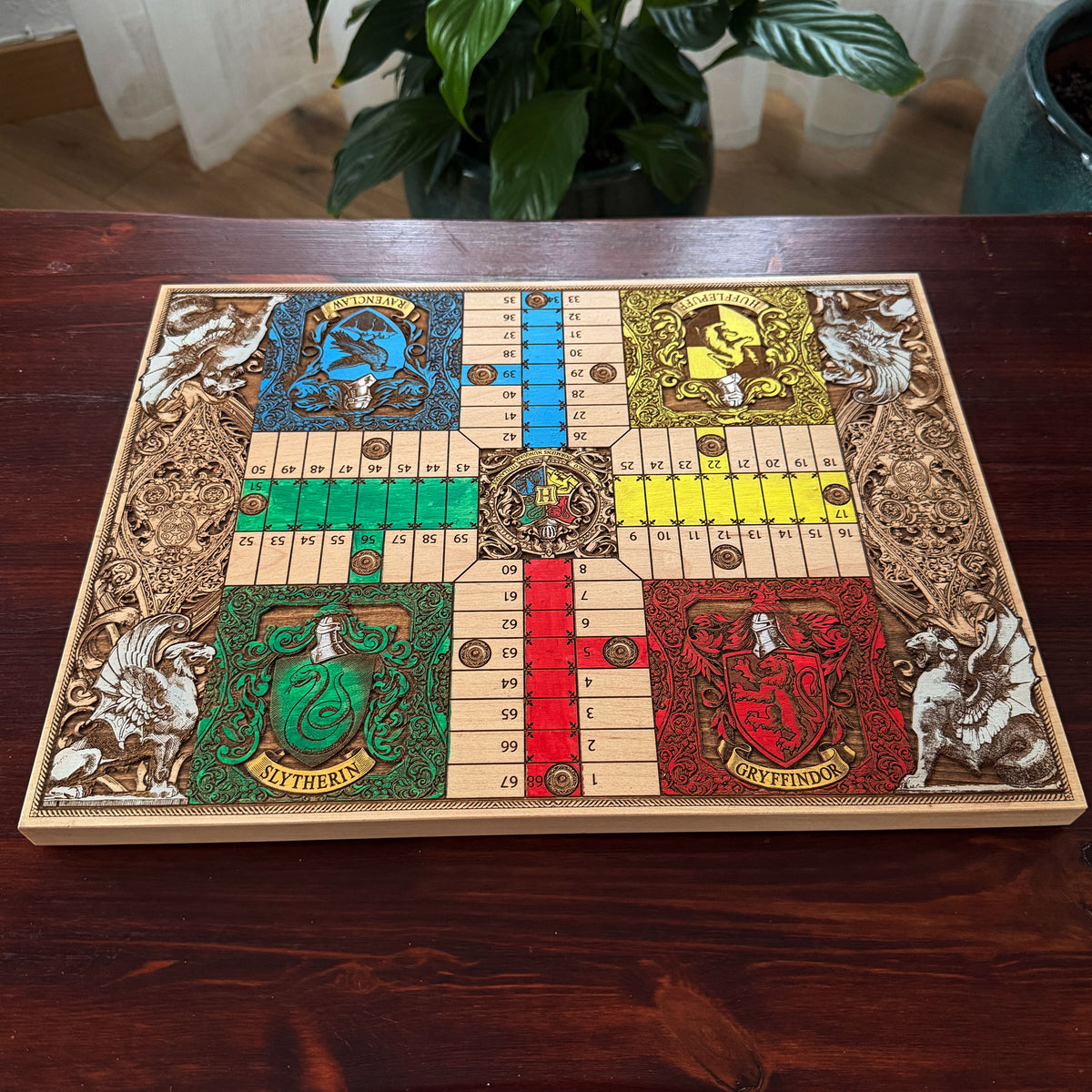 Harry Potter board game featuring four Hogwarts houses with detailed engraved fantasy artwork