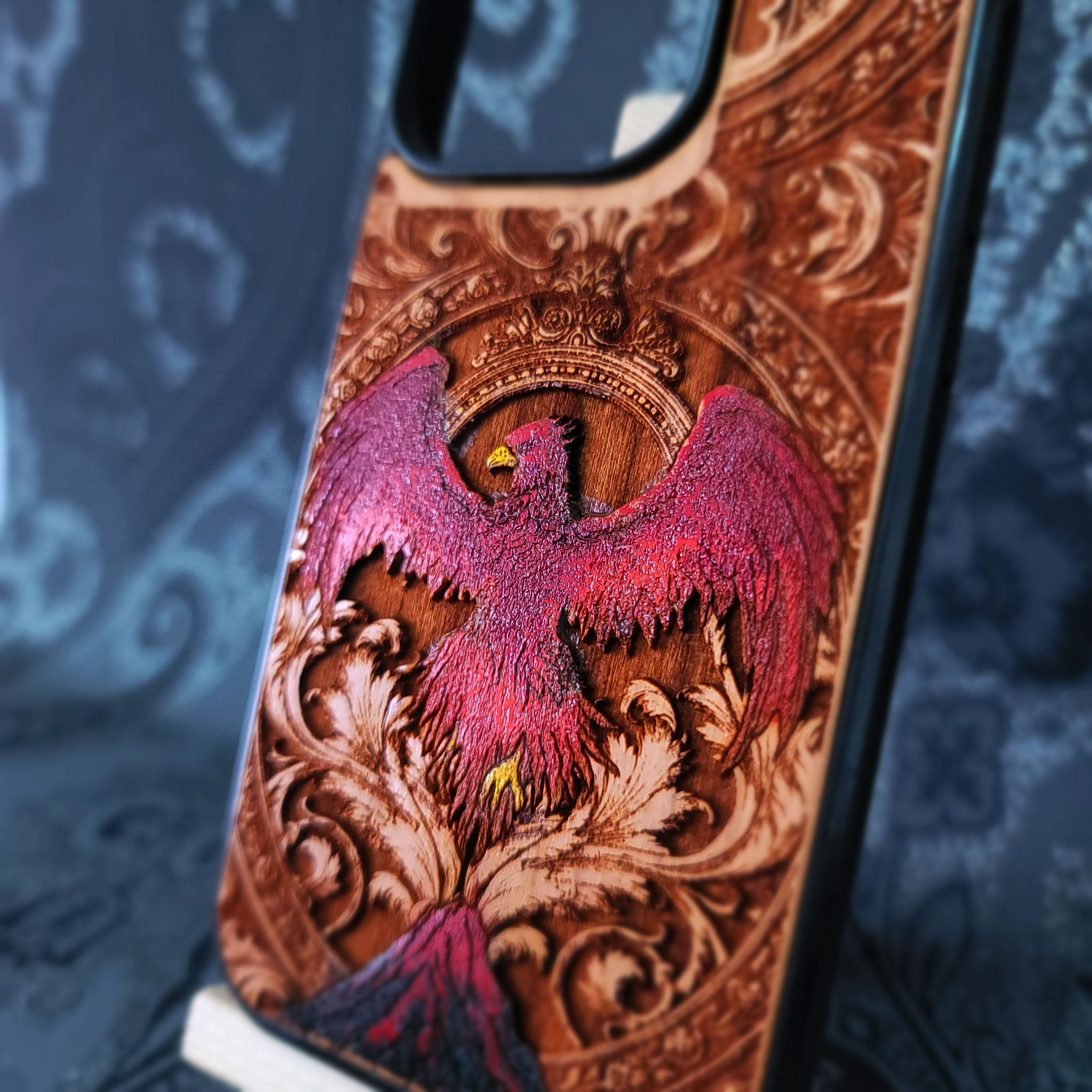 Deep laser engraved wooden phone case featuring a mythical phoenix bird with detailed flames and wings on natural wood for iPhone and Samsung Galaxy models.