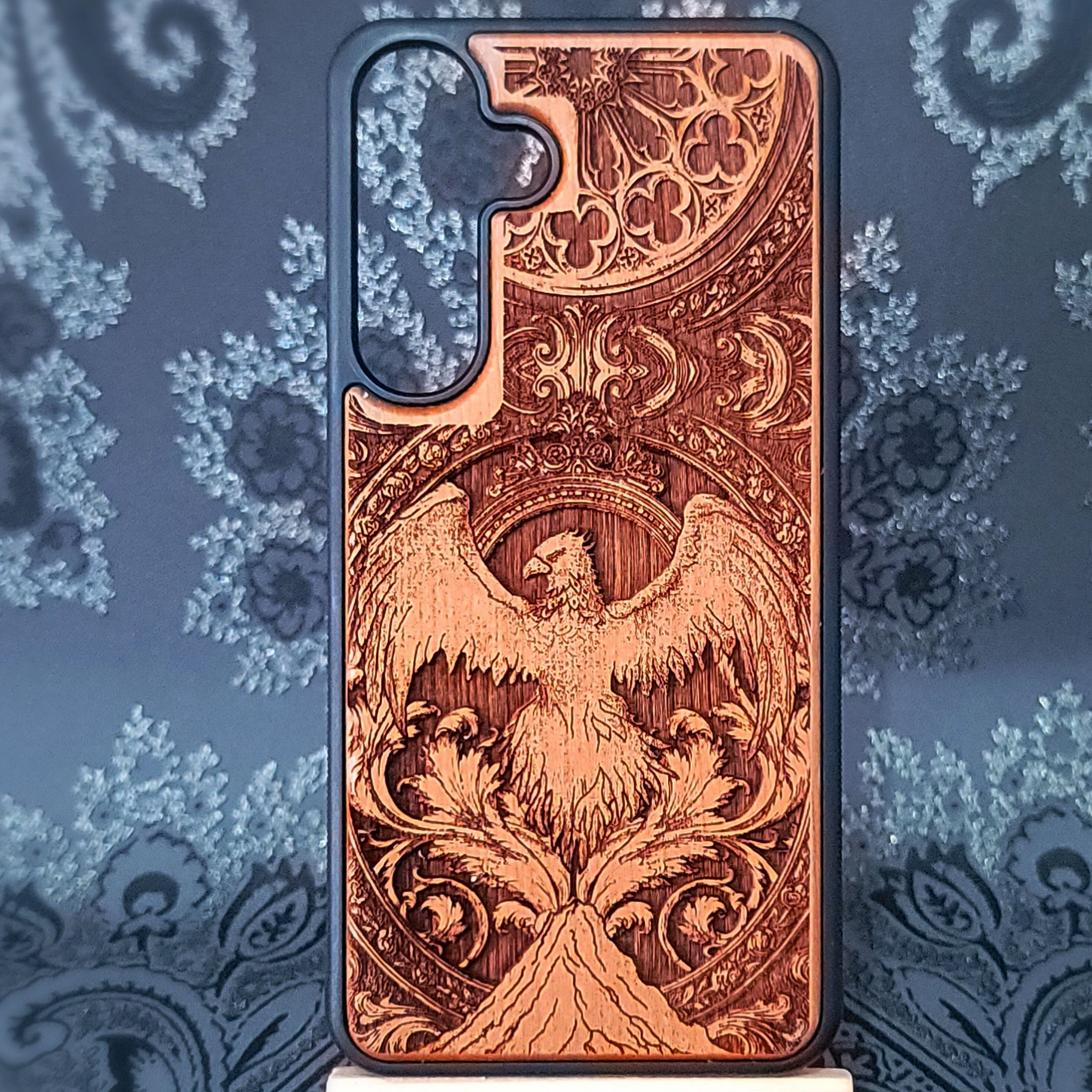 Deep laser engraved wooden phone case featuring a mythical phoenix bird design on natural wood. Available for iPhone and Samsung Galaxy.