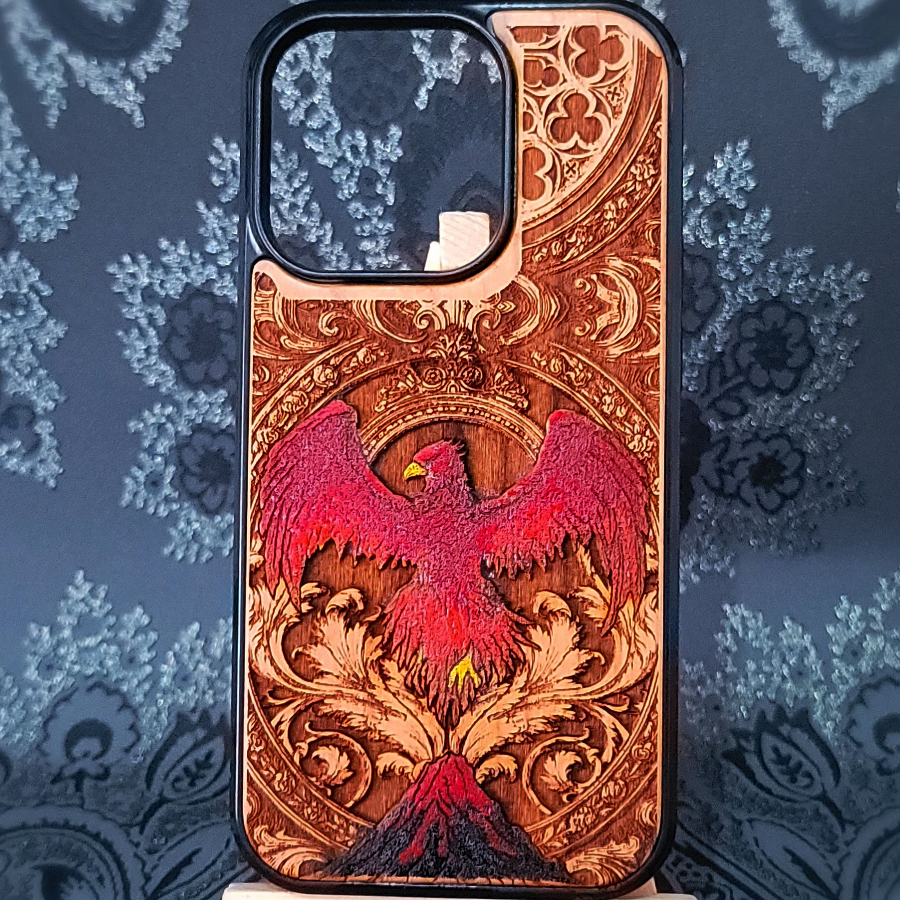 Deep laser engraved wooden phone case featuring a mythical phoenix bird with detailed flames and wings on natural wood for iPhone and Samsung Galaxy models.