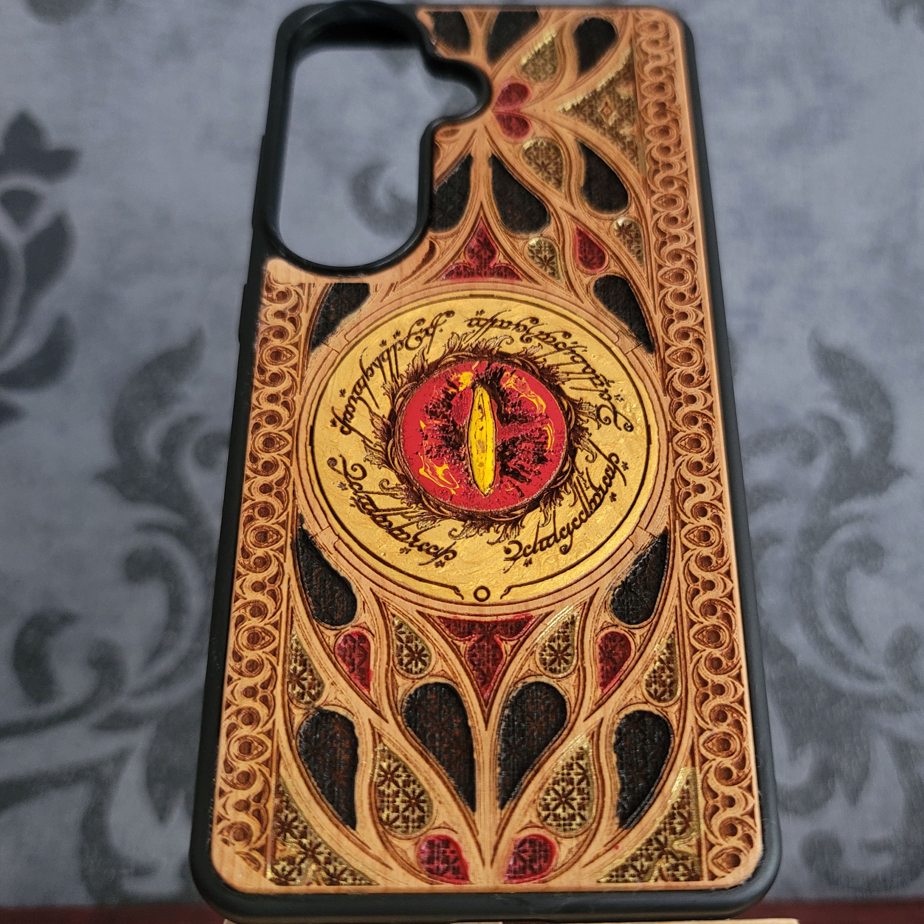 Hand-painted wood phone case featuring the Eye of Sauron surrounded by intricate Elvish script and vibrant colored patterns.