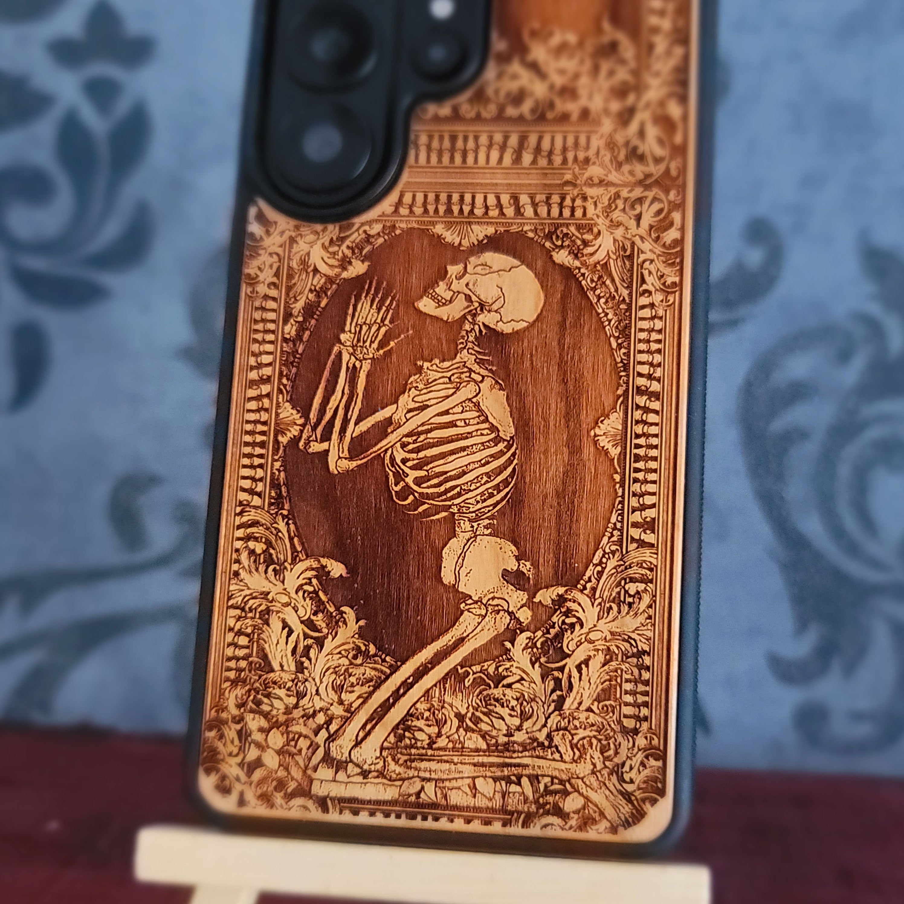 Praying skeleton wood phone case for iPhone and Samsung Galaxy, featuring gothic anatomical art with deep laser engraving.