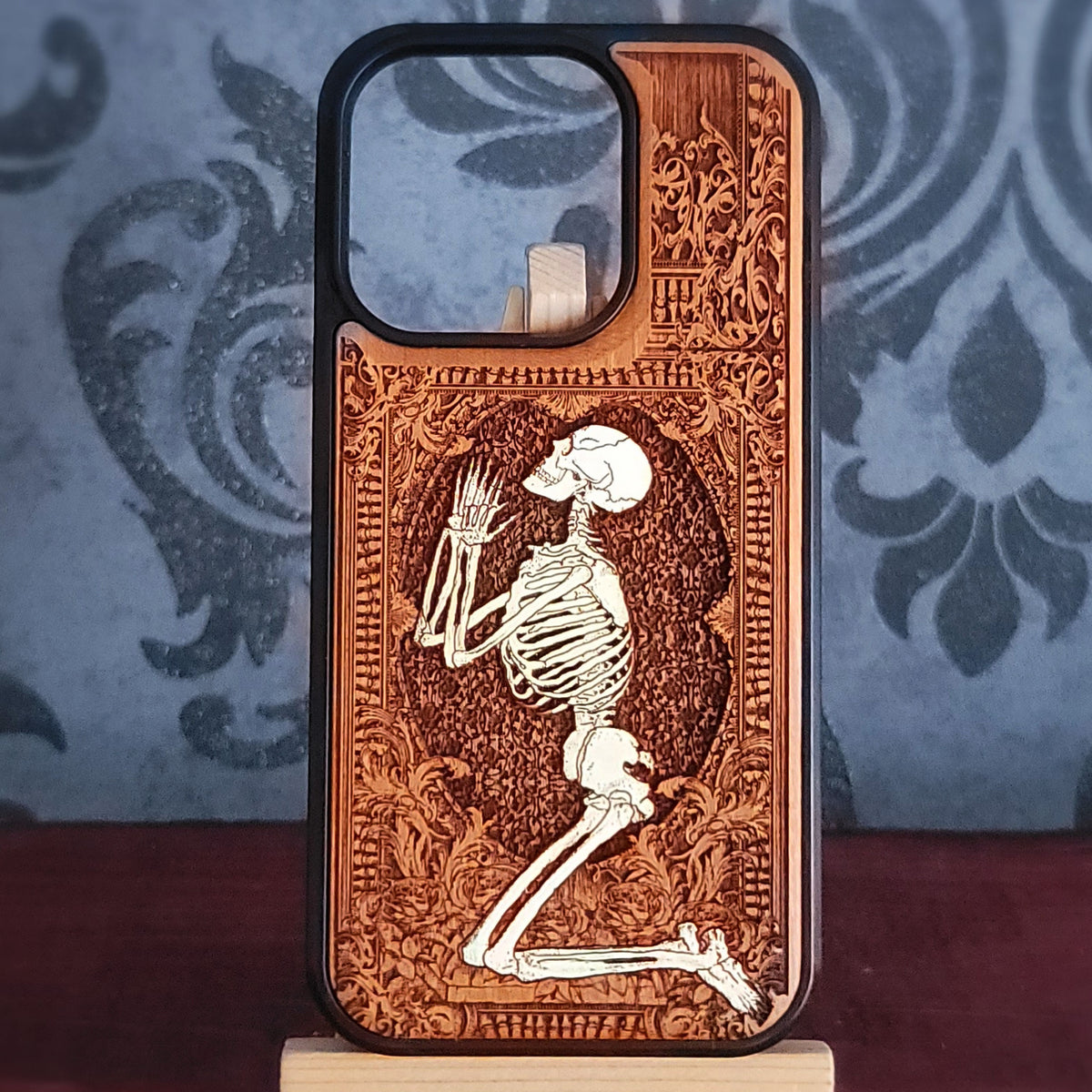 Hand-painted wooden phone case featuring a laser-engraved gothic praying skeleton design on cherrywood.