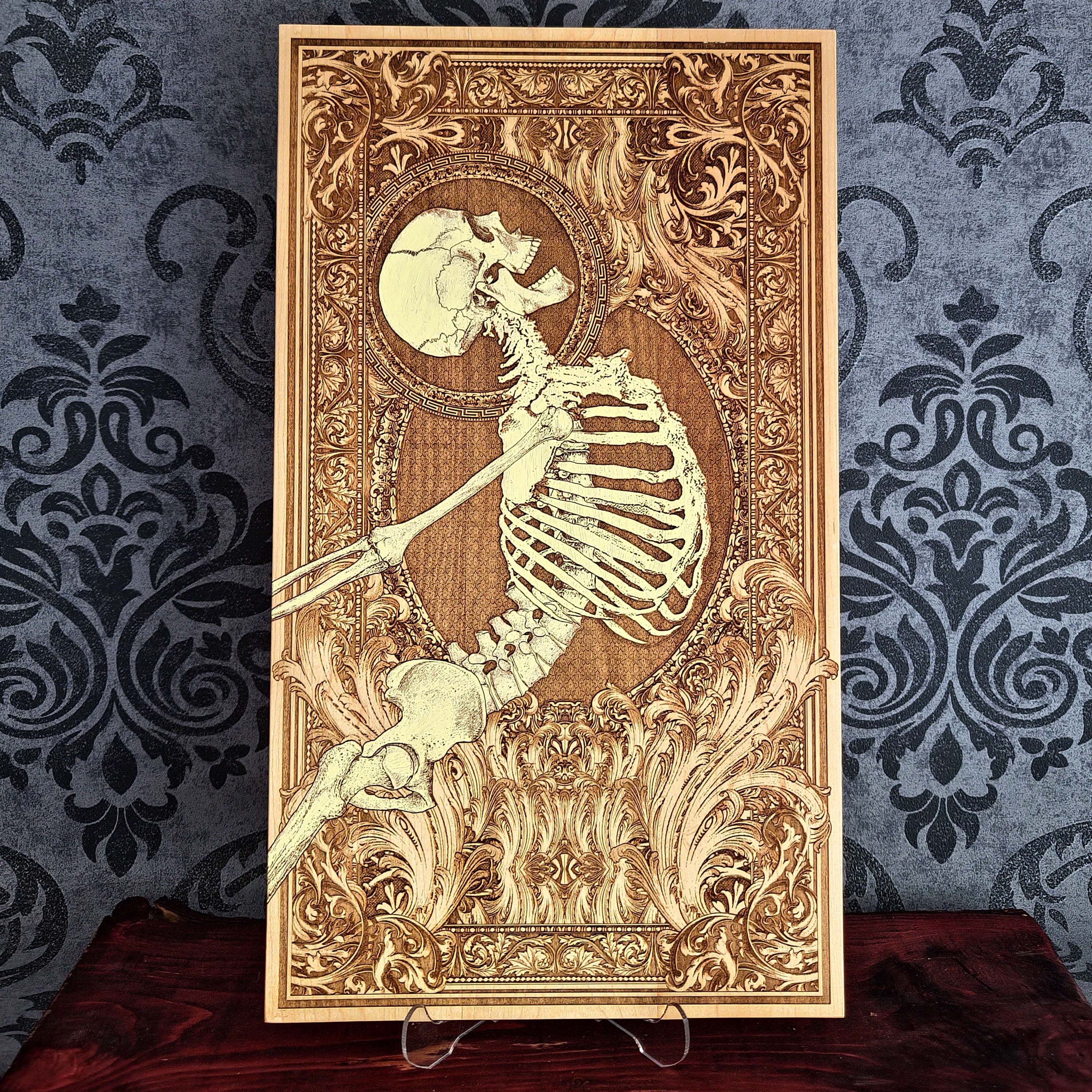 A rectangular wooden wall art plaque featuring a detailed laser-engraved skeleton , set against an ornate baroque-style border.