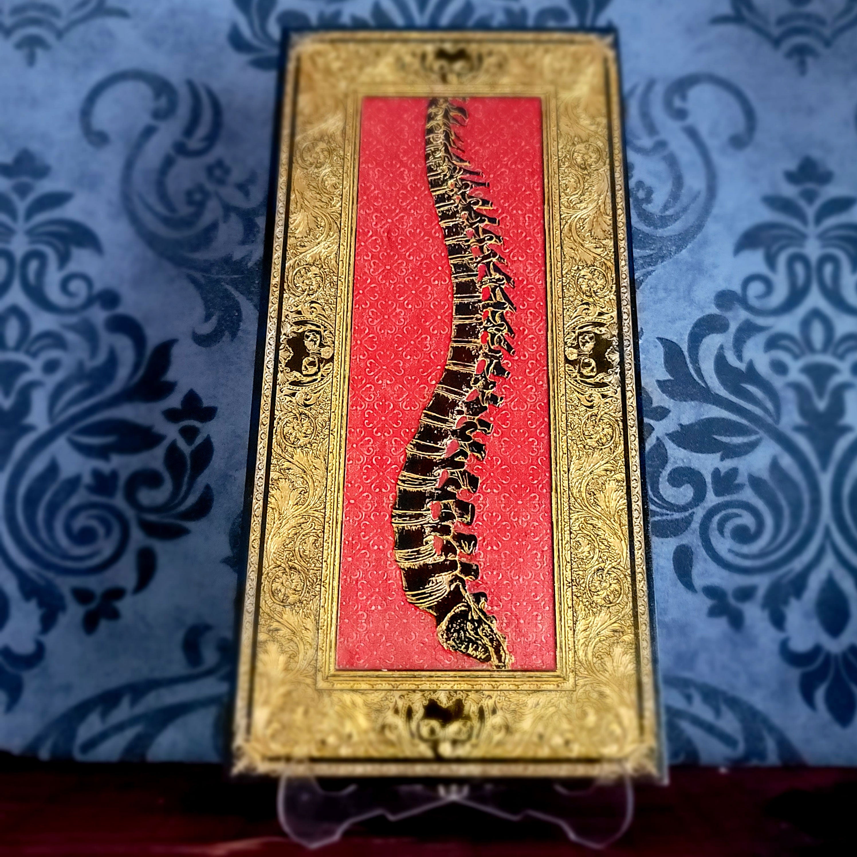 Decorative box with a spine design on a red background, placed on a blue patterned fabric.