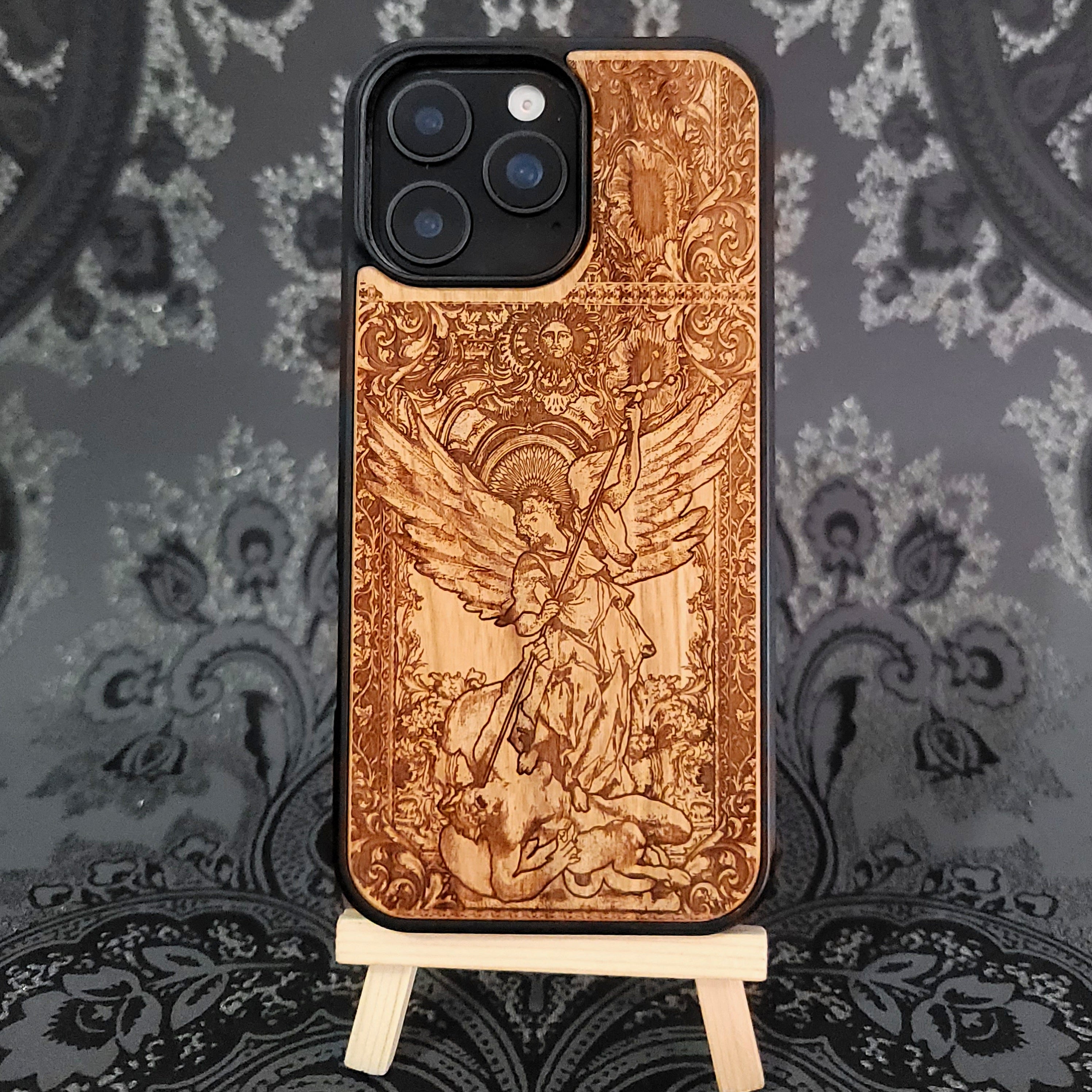 Deep laser engraved wooden phone case featuring Saint Michael Archangel fighting a demon with detailed religious artwork on natural wood for iPhone and Samsung Galaxy models.