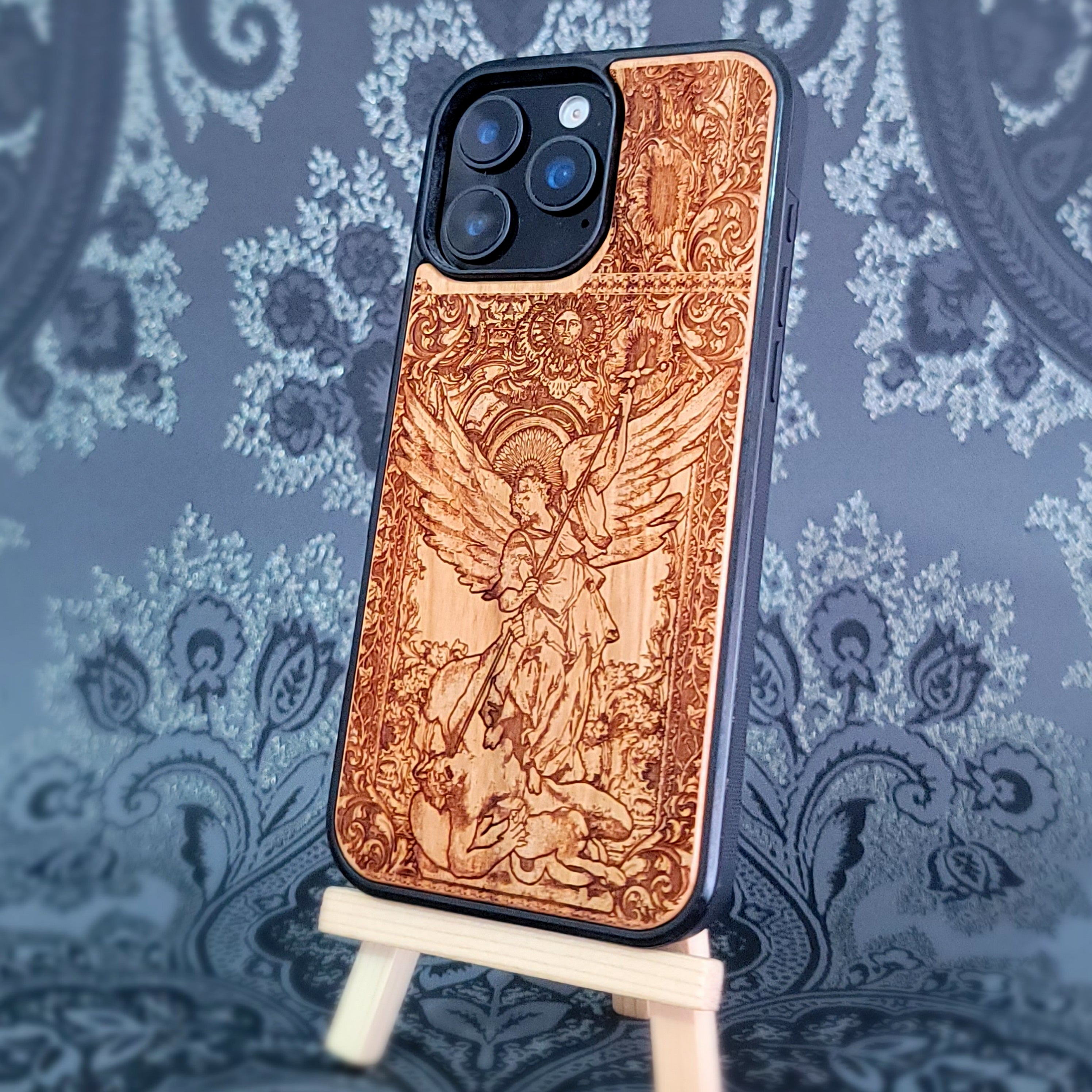 Deep laser engraved wooden phone case featuring Saint Michael Archangel fighting a demon with detailed religious artwork on natural wood for iPhone and Samsung Galaxy models.