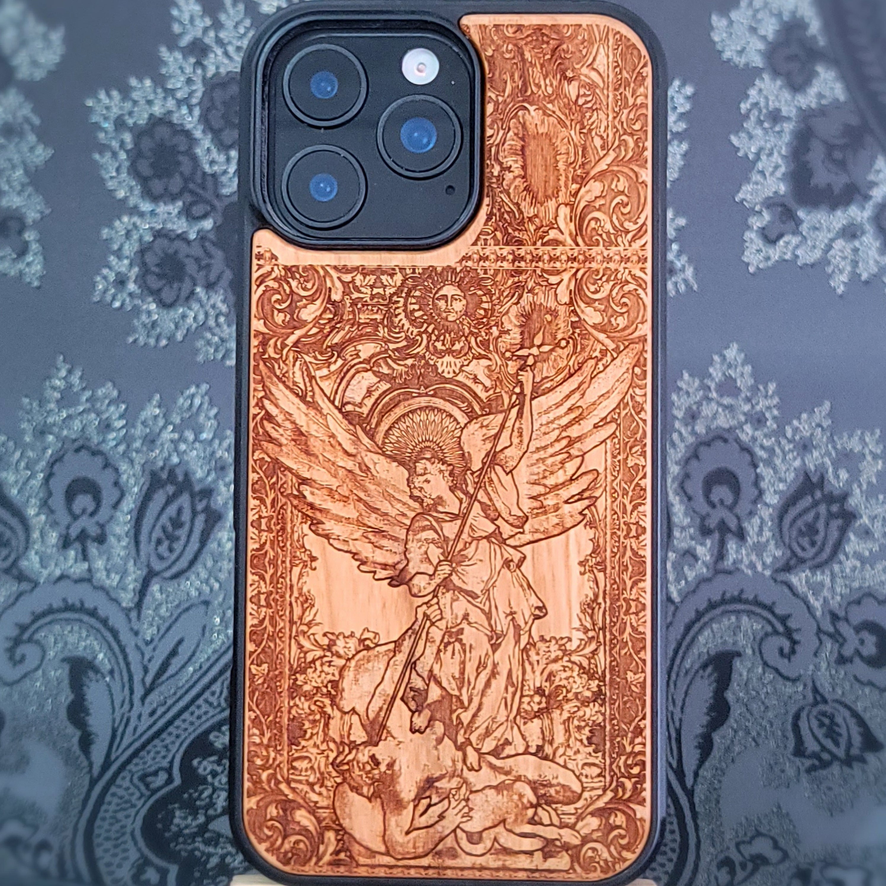 Deep laser engraved wooden phone case featuring Saint Michael Archangel fighting a demon with detailed religious artwork on natural wood for iPhone and Samsung Galaxy models.
