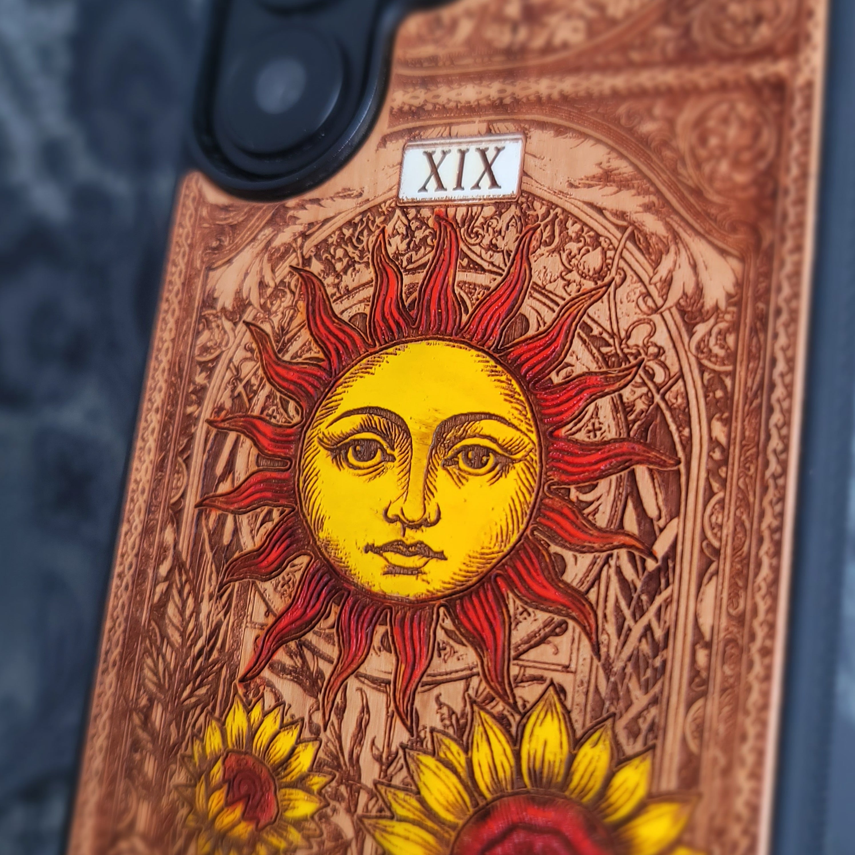 Deep laser engraved wooden phone case featuring The Sun tarot card with celestial mystical details on natural wood for iPhone and Samsung Galaxy models.