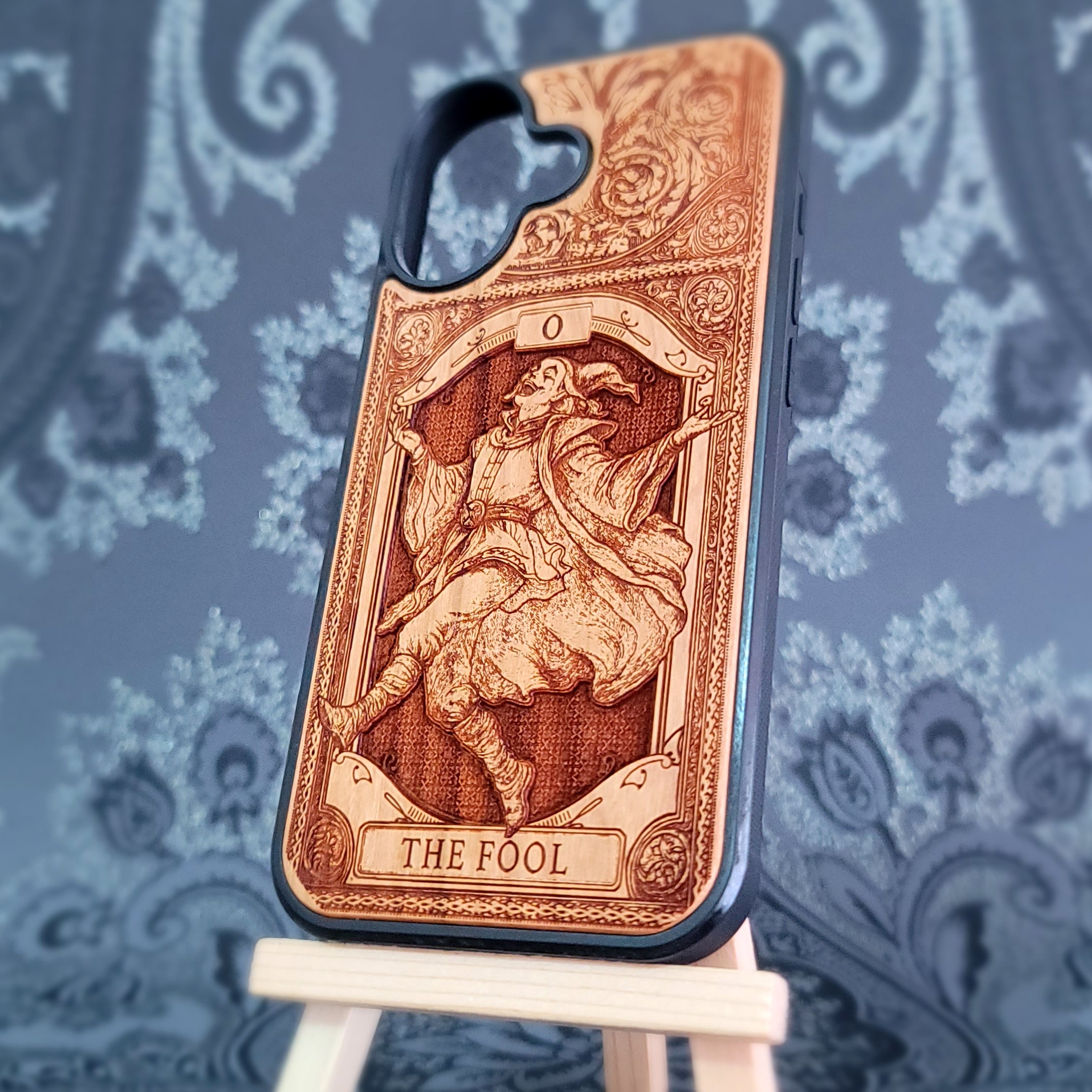 Deep laser engraved wooden phone case featuring The Fool tarot card with mystical celestial details on natural wood for iPhone and Samsung Galaxy models.