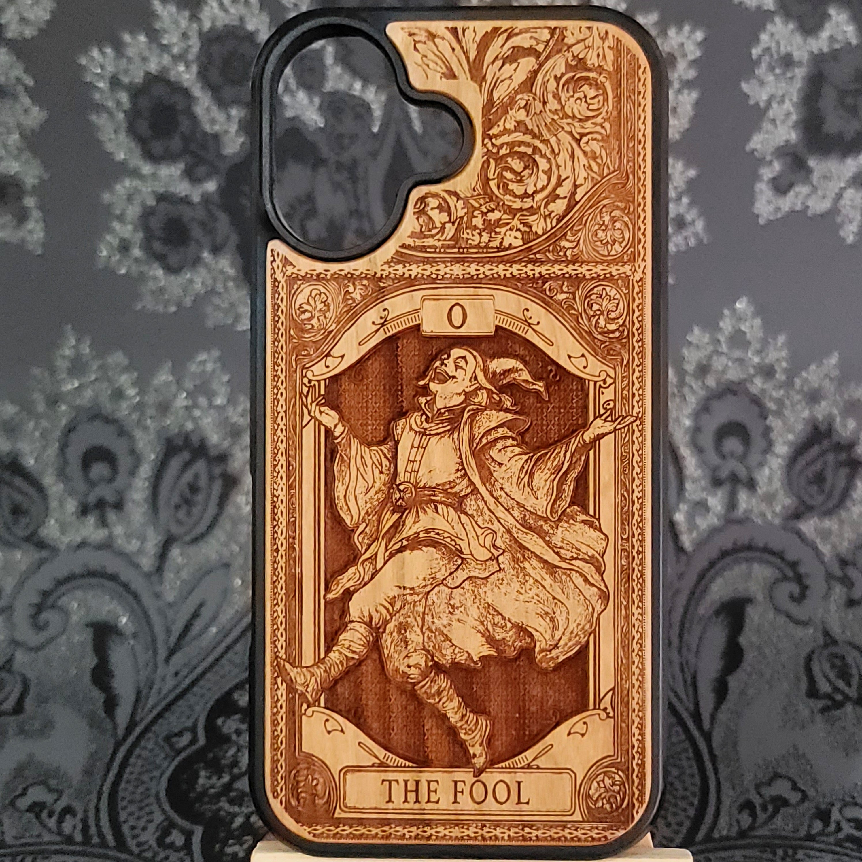 Deep laser engraved wooden phone case featuring The Fool tarot card with mystical celestial details on natural wood for iPhone and Samsung Galaxy models.