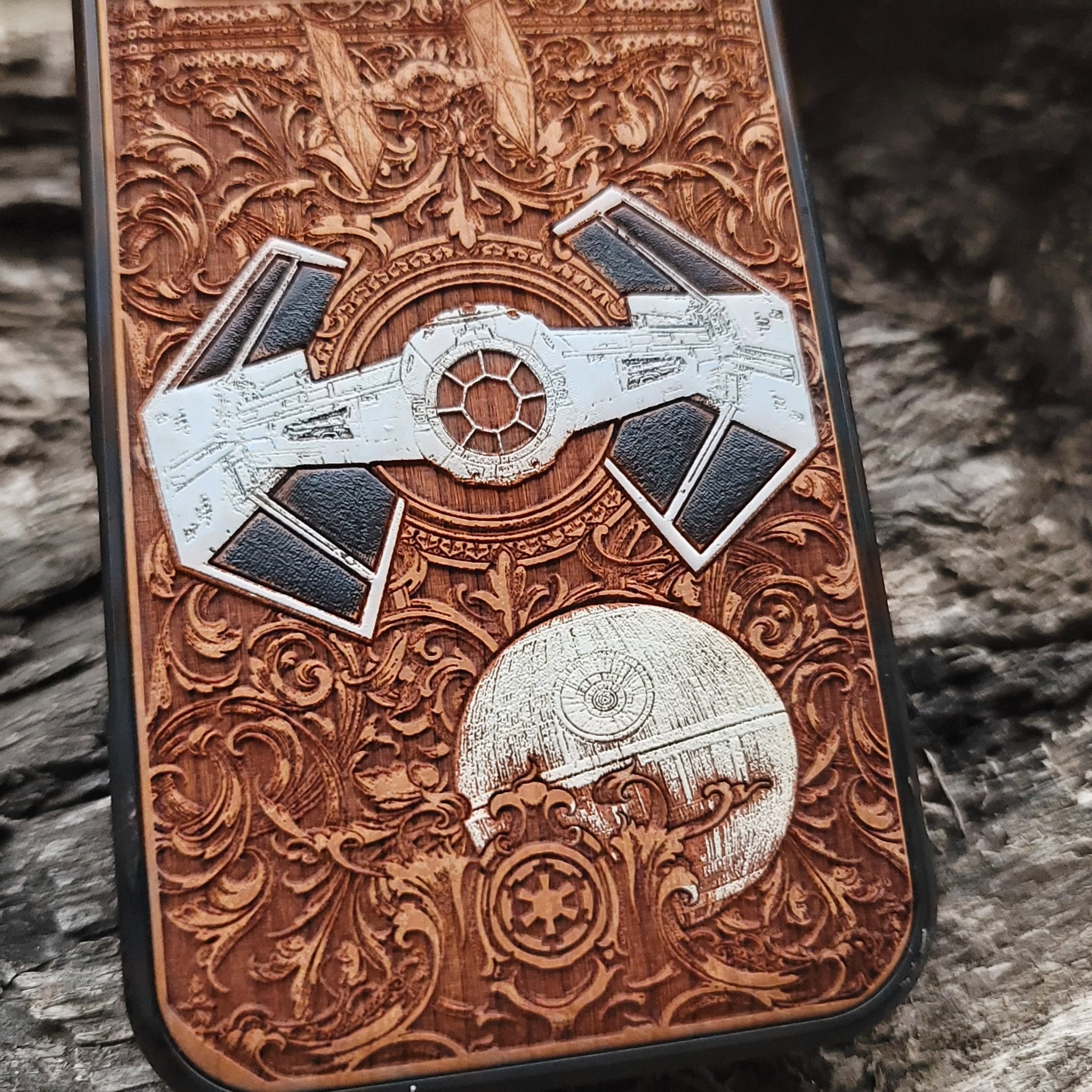 Close-up of handcrafted cherry wood phone case featuring intricate Star Wars-inspired spaceship engraving.