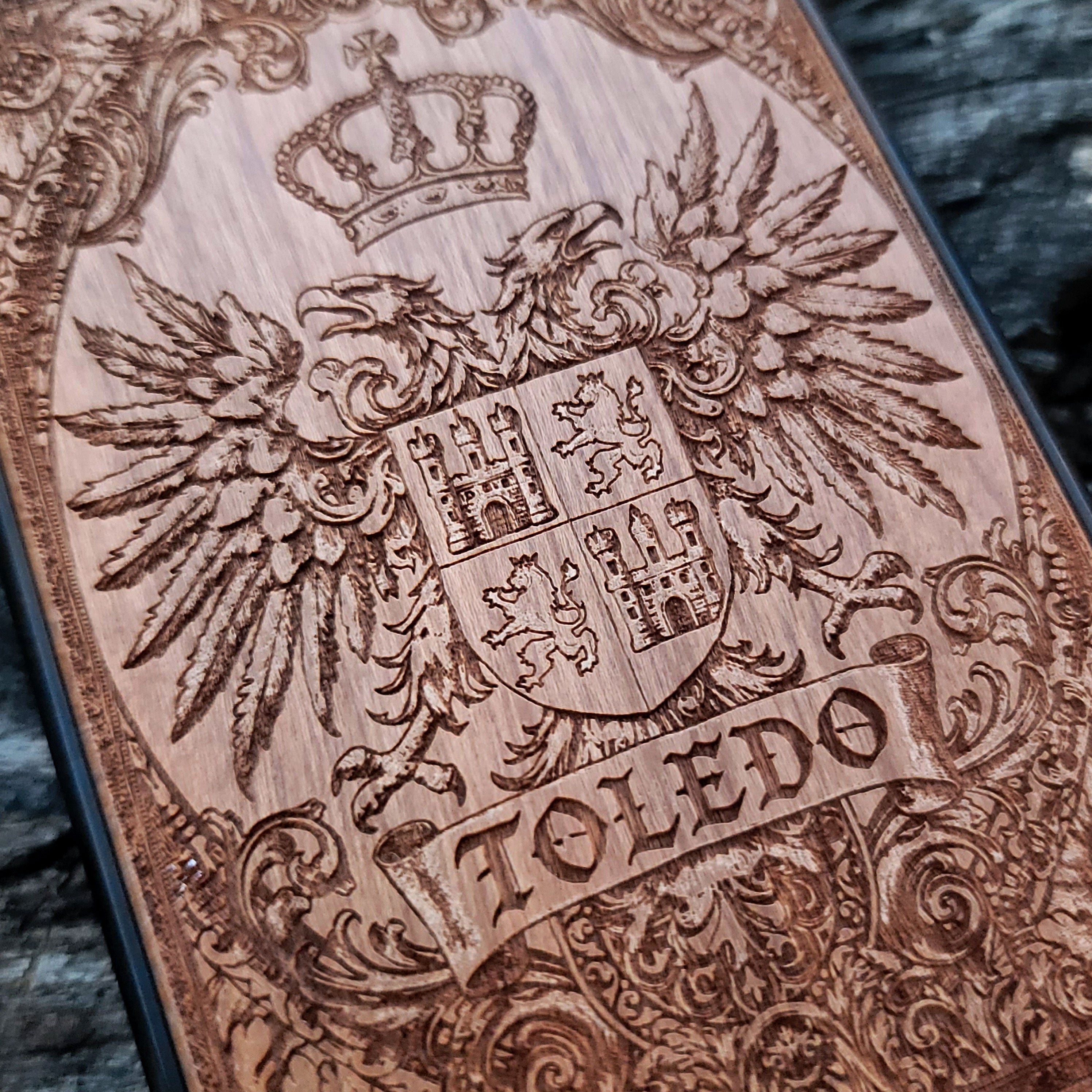 Close-up of Toledo coat of arms engraved on cherry wood phone cover.