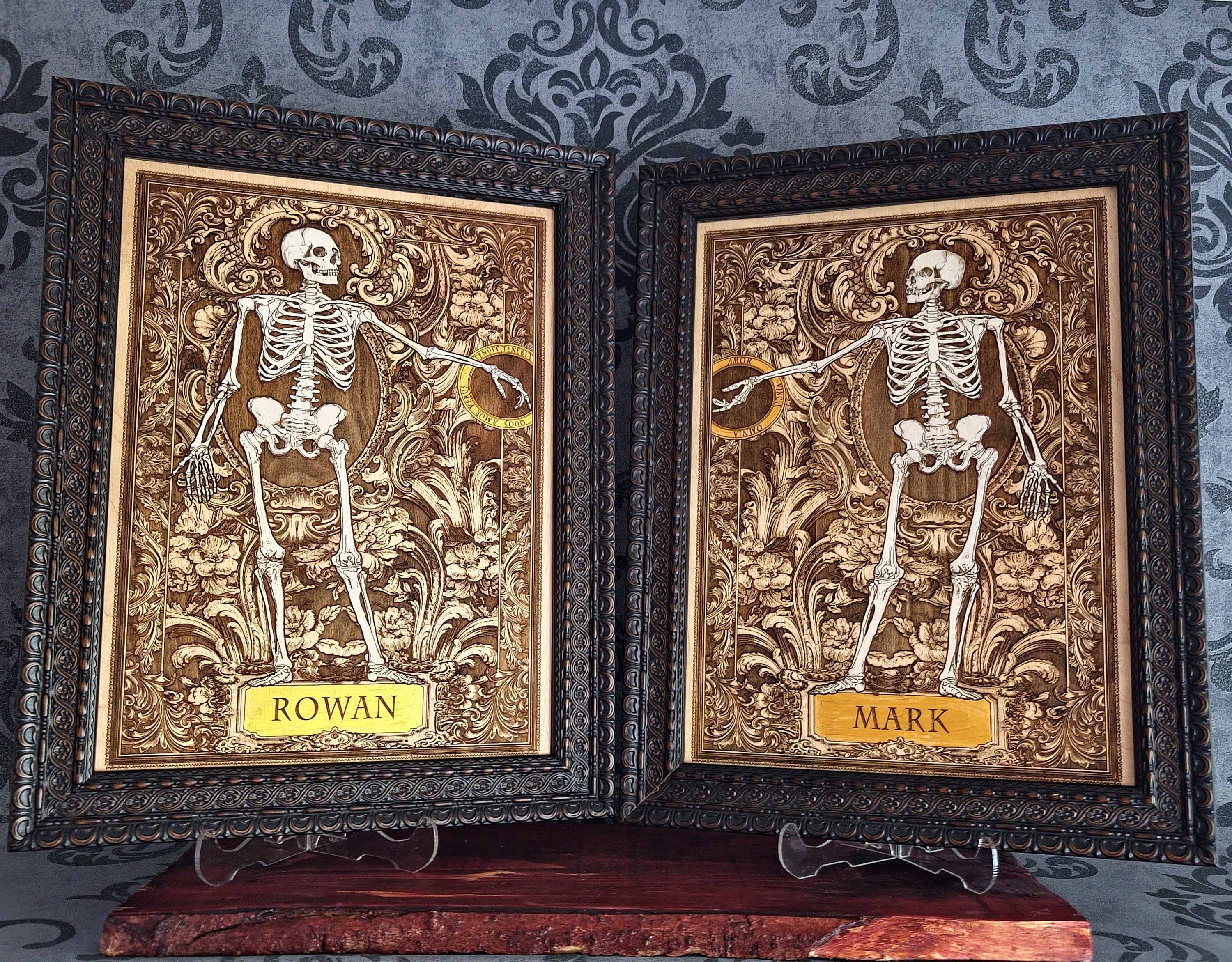 Two framed gothic-style name plates featuring embossed skeletons on ornate gold and brown backgrounds,