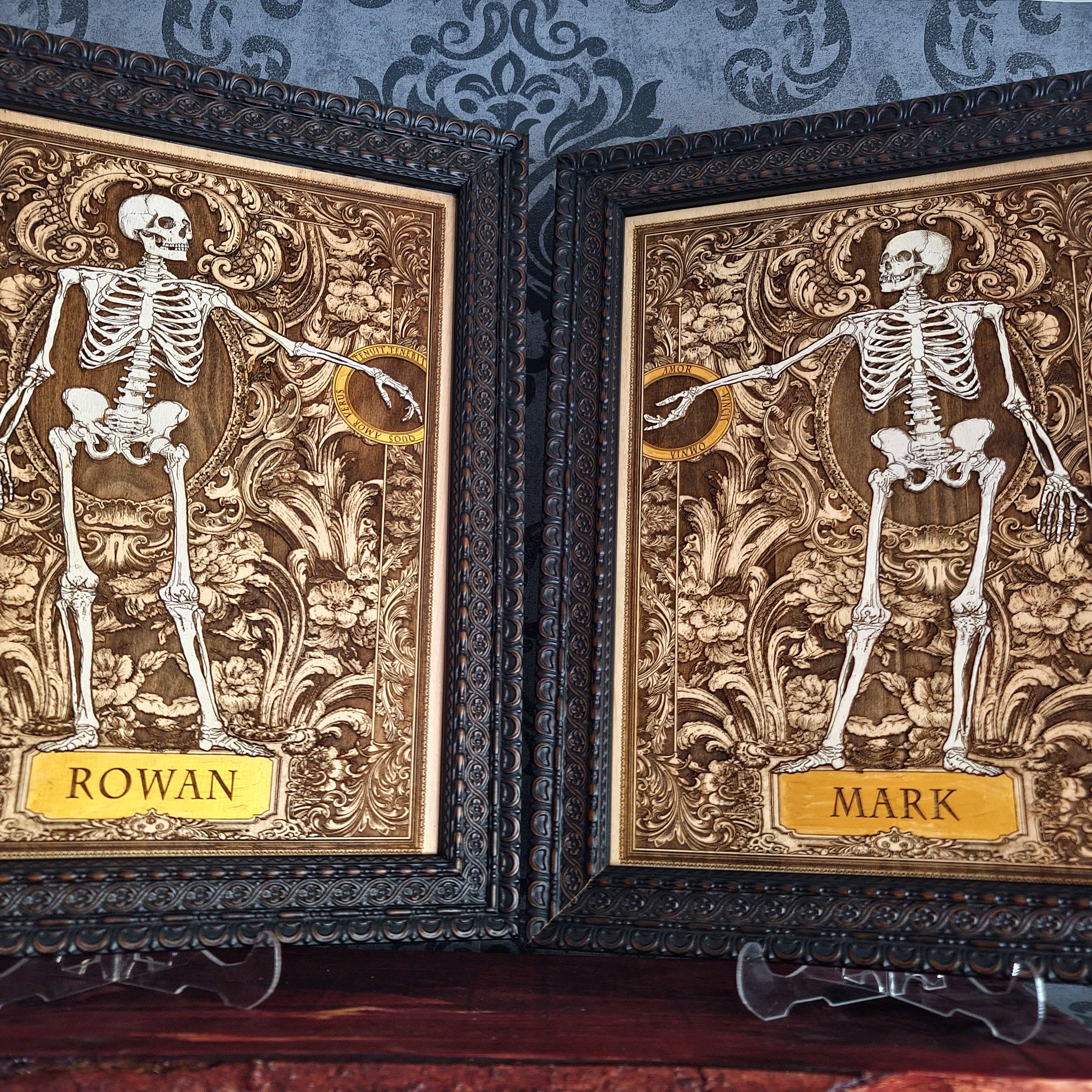 Two framed gothic-style skeleton art prints with ornate gold and brown baroque backgrounds,