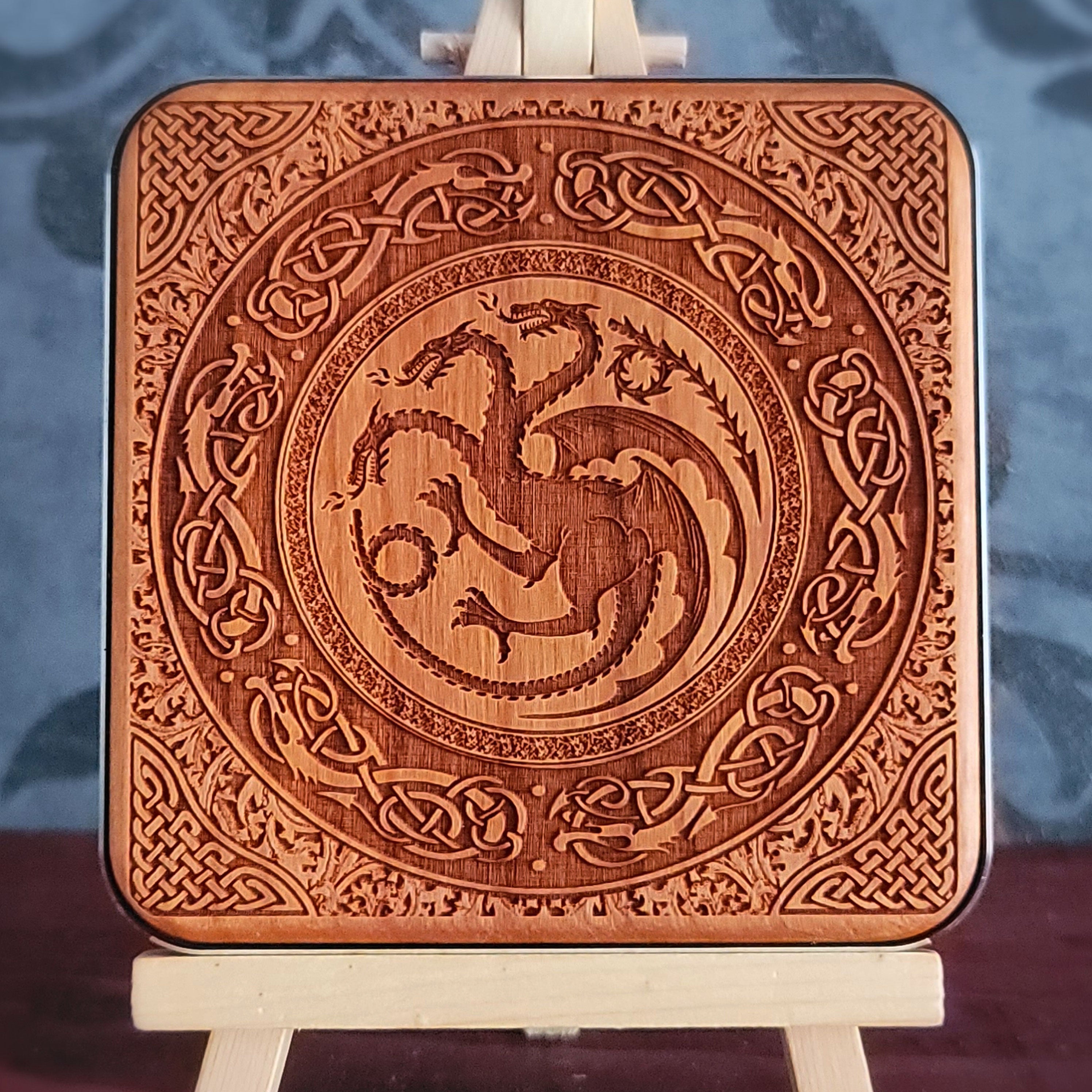 A wooden wireless charger with a laser-etched design of a three-headed dragon surrounded by intricate Celtic knotwork.