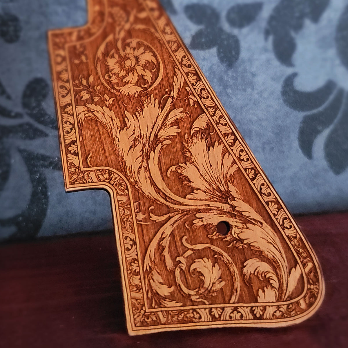 Close up of vintage flourish design engraved into natural cherry wood guitar pickguard