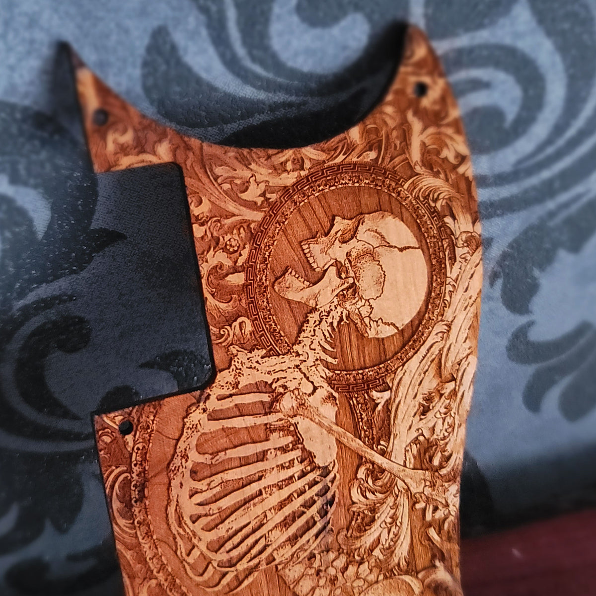 Close up of anatomical skeleton artwork engraved into real cherry wood guitar pickguard