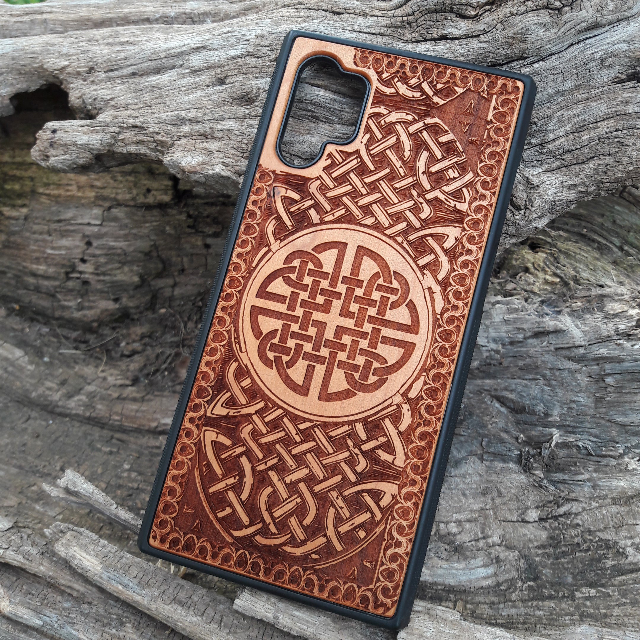Laser-engraved wooden phone case showcasing a stunning Celtic knotwork design, intricately detailed for a timeless look. This durable and artistic case is compatible with iPhone , 15, 14, 13, 12, 11, Pro Max, Mini, and Samsung Galaxy S, S24, S23, S22, S21, S20 Ultra, Plus, Note 20. A perfect blend of craftsmanship and functionality for those who appreciate Celtic art.
