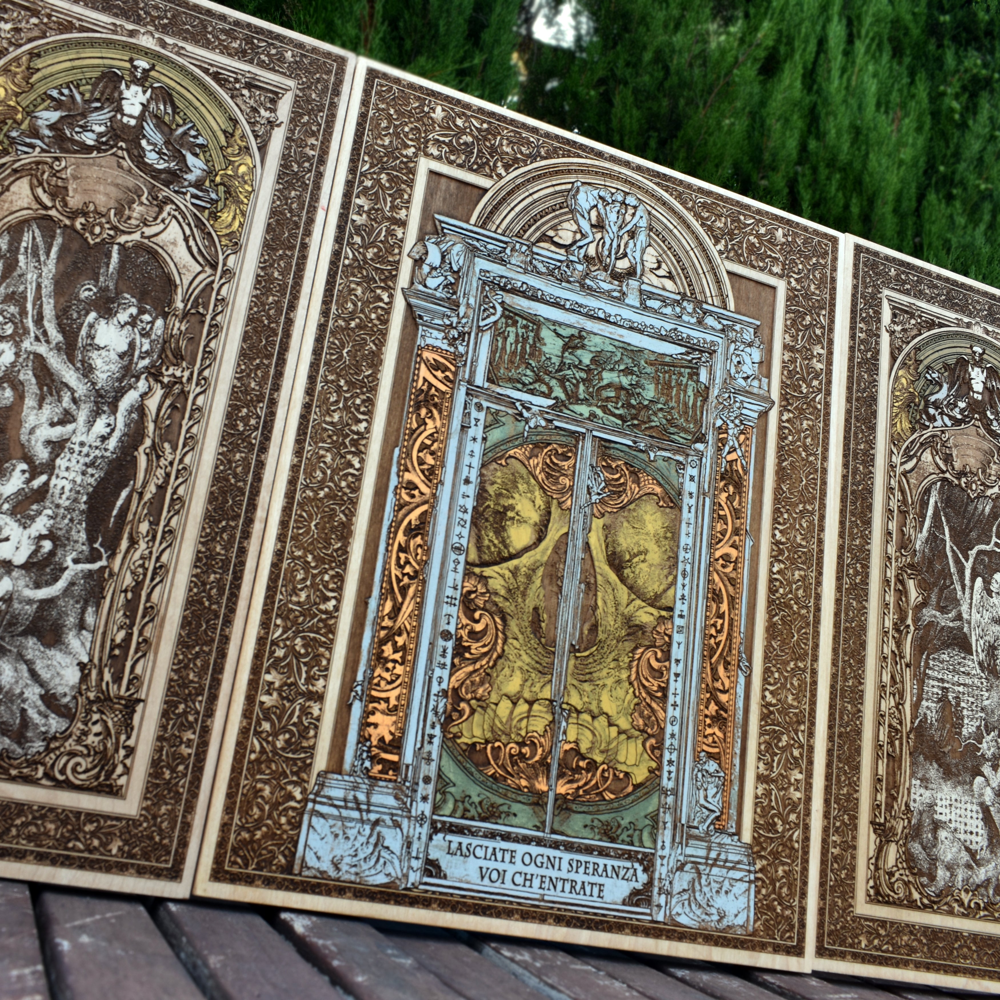 Dark, intricately engraved maple wood artwork featuring hellish figures, skulls, and gothic motifs in a stunning triptych design.