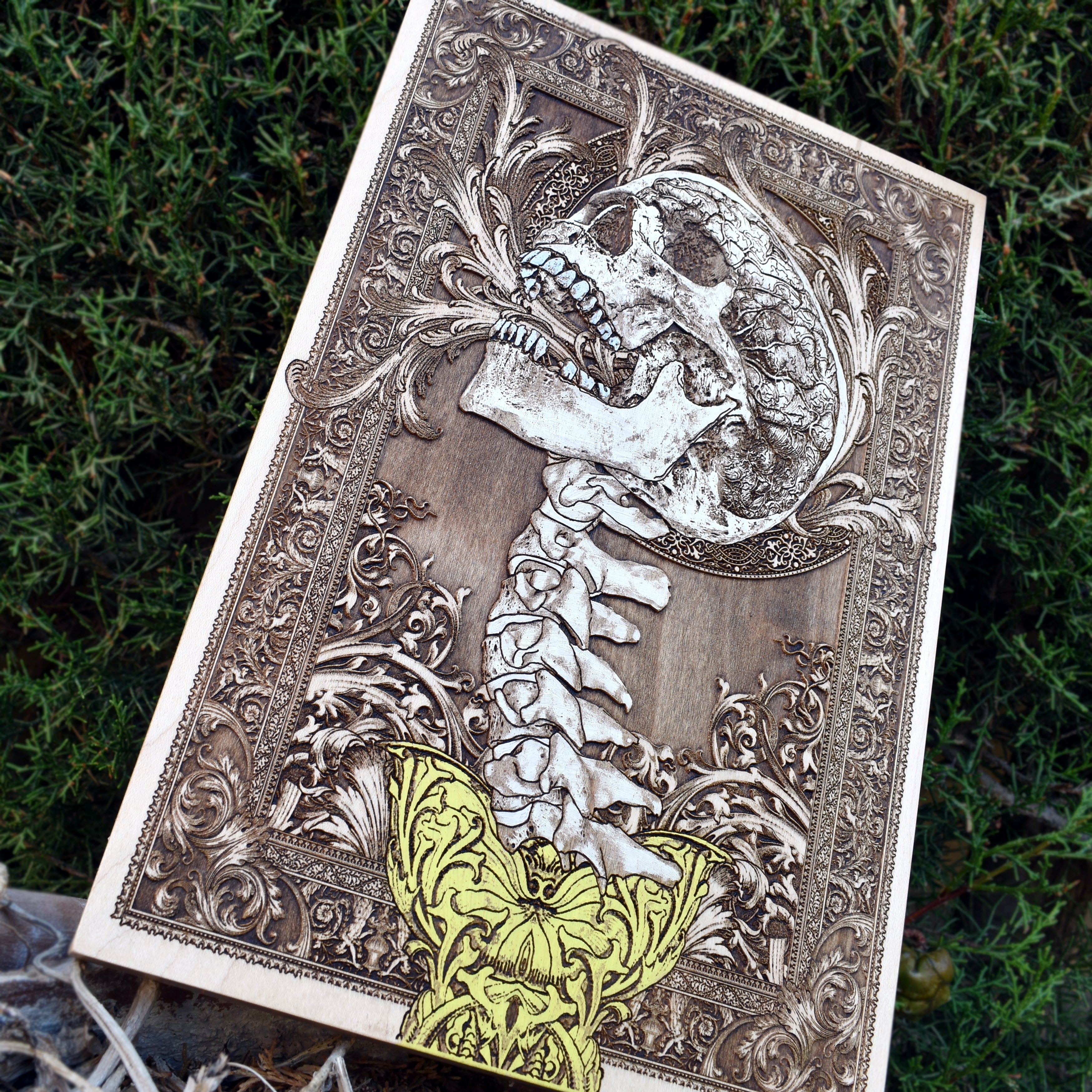 Macabre wood wall art of a skull in agony with vertebrae, laser-engraved detail.