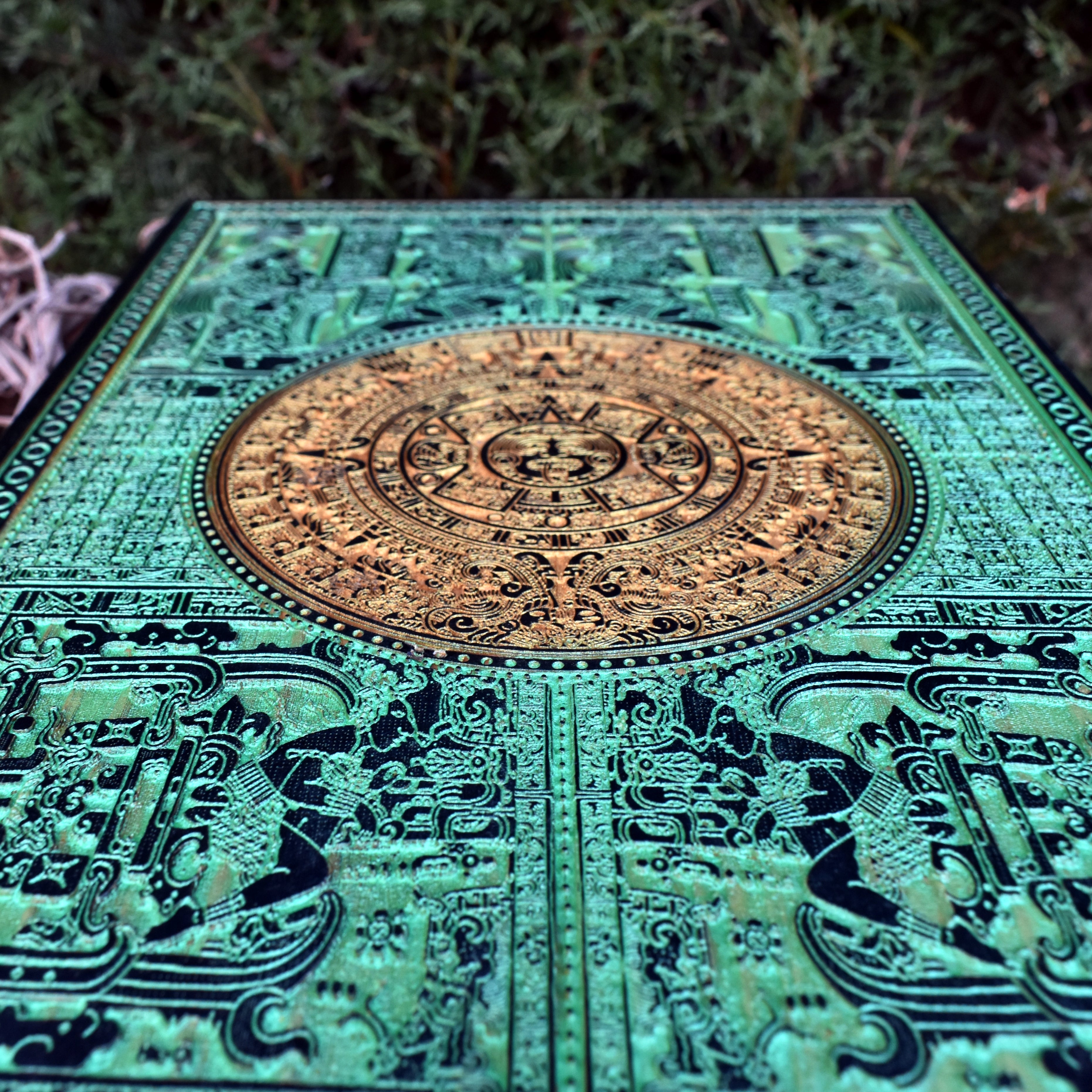 Wooden Aztec calendar with laser-etched green accents for boho interiors.