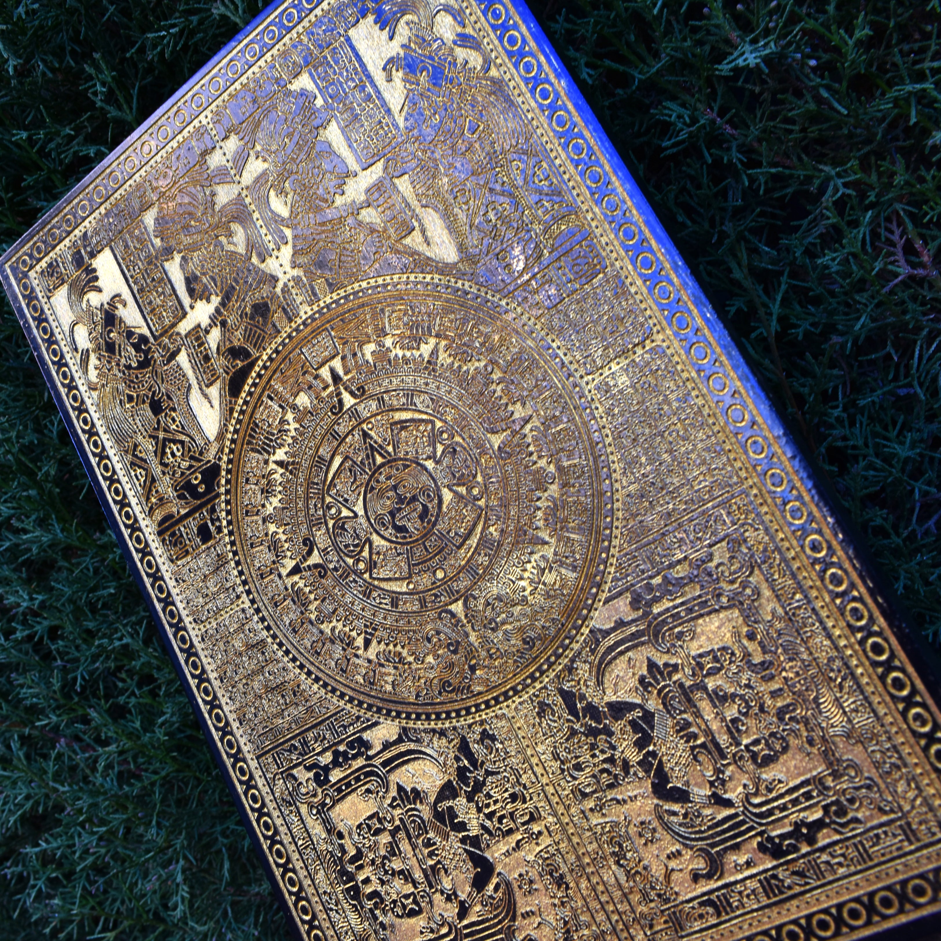 Aztec sunstone calendar artwork etched into wood, handcrafted wall decor.