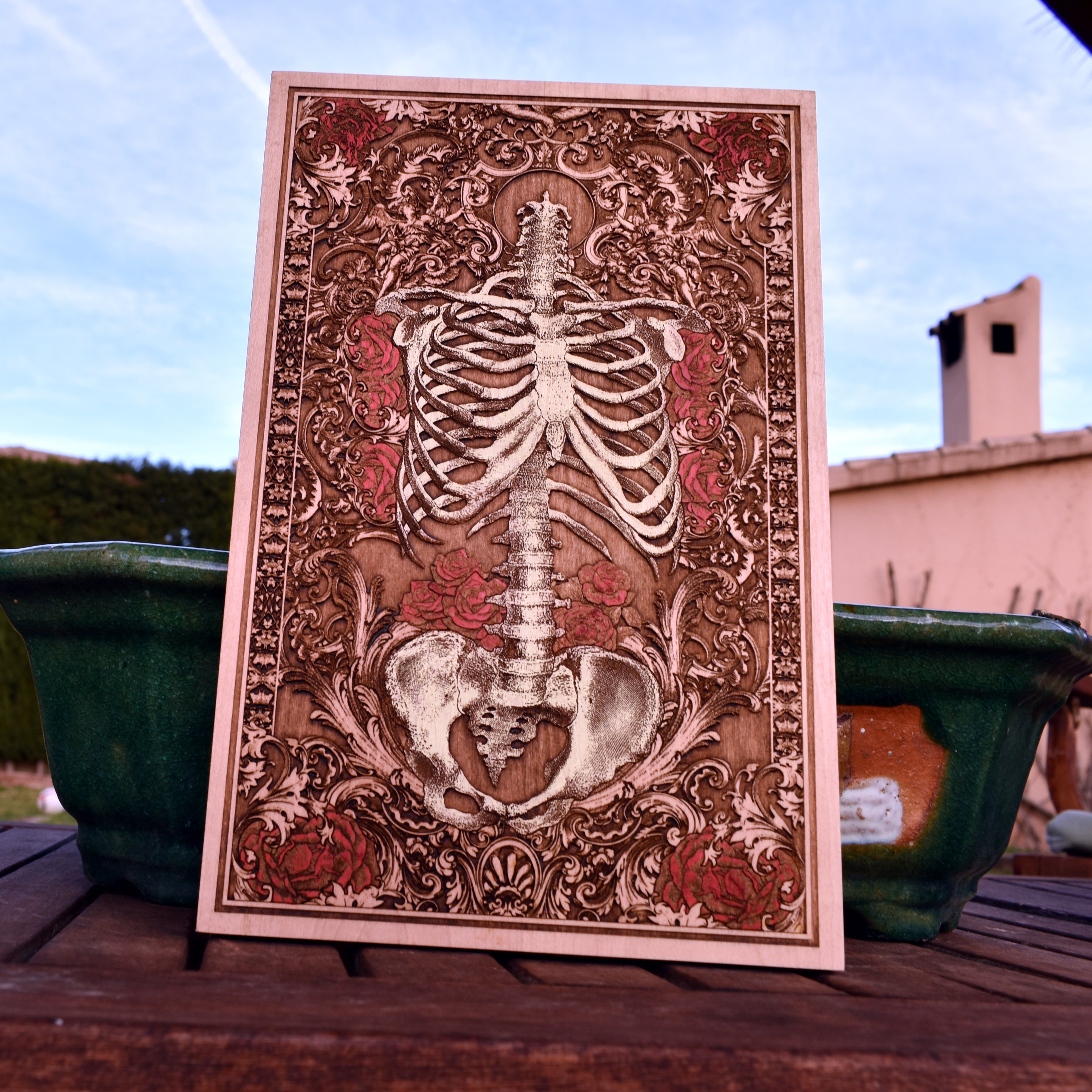 Gothic anatomical skeleton artwork on wood with roses and bone details.