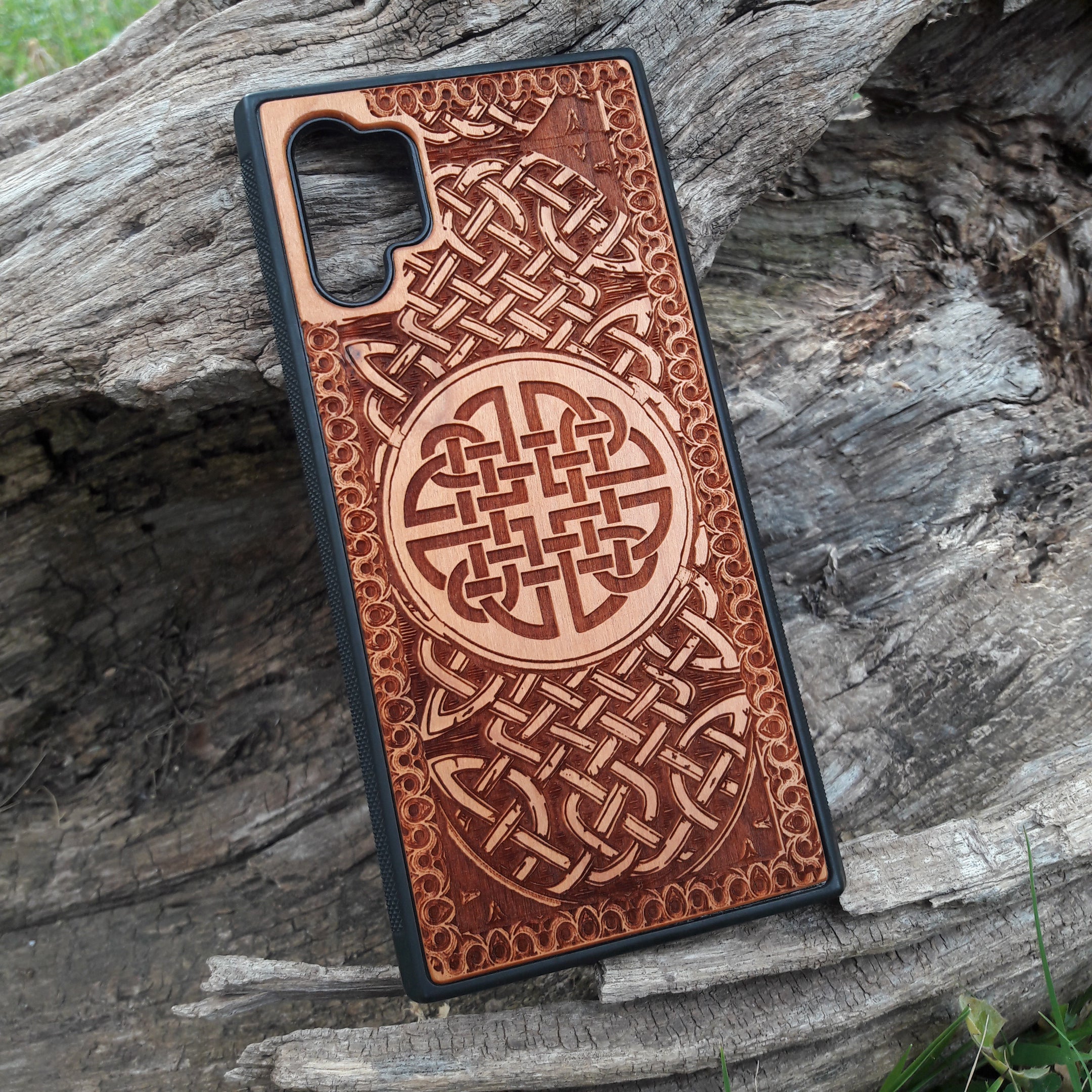 Laser-engraved wooden phone case showcasing a stunning Celtic knotwork design, intricately detailed for a timeless look. This durable and artistic case is compatible with iPhone , 15, 14, 13, 12, 11, Pro Max, Mini, and Samsung Galaxy S, S24, S23, S22, S21, S20 Ultra, Plus, Note 20. A perfect blend of craftsmanship and functionality for those who appreciate Celtic art.