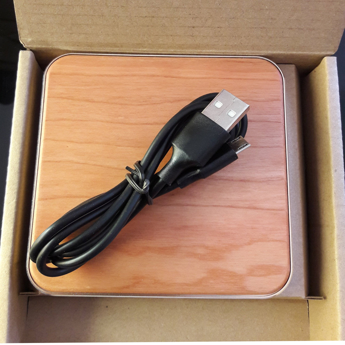 Engraved anatomical heart cherrywood wireless charger, open package showing the wood charger and USB cable