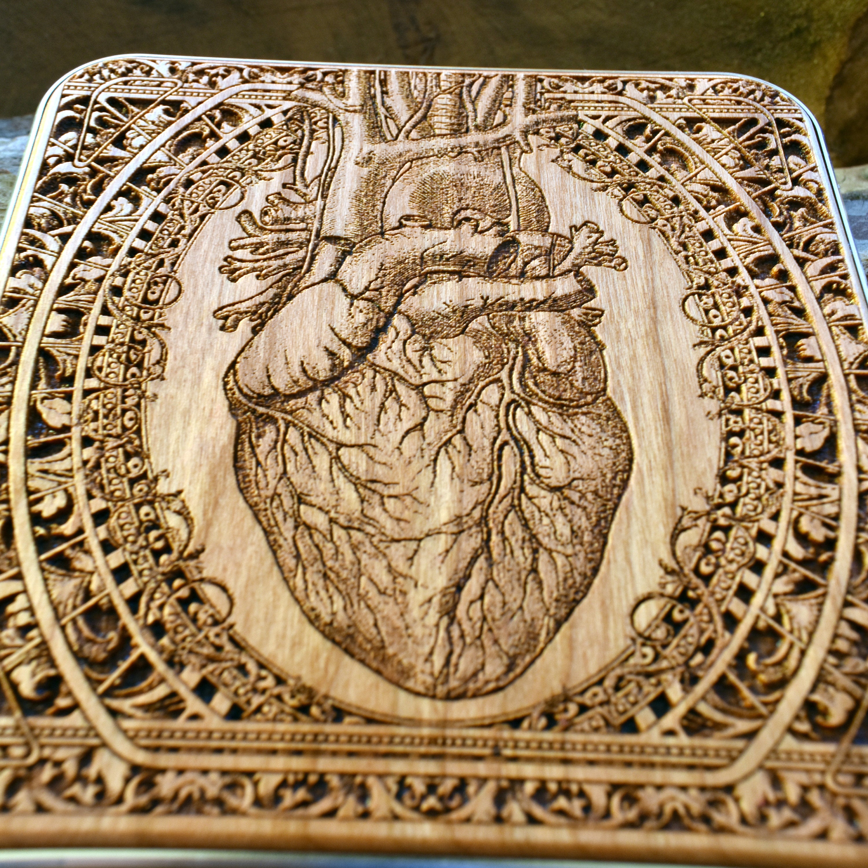 Engraved anatomical heart cherrywood wireless charger, front detail of the heart vessels and decorative border