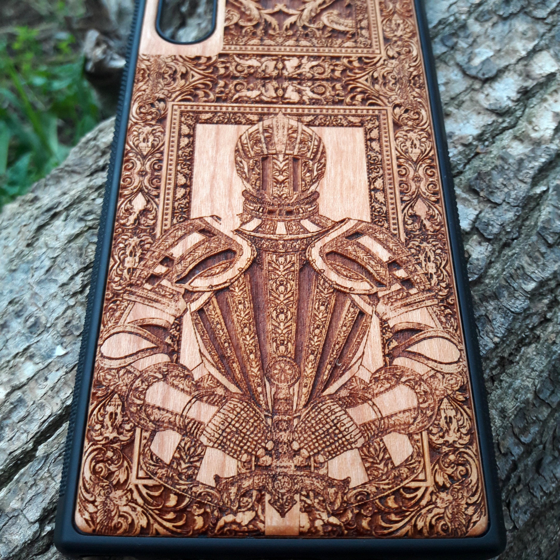 Wooden phone case featuring a detailed engraving of a medieval knight's armor, framed by intricate gothic designs. Ideal for iPhone , iPhone 15, iPhone 14, iPhone 13, Samsung Galaxy S, S24, S23, S22, and more. Perfect for lovers of history, knights, and medieval or gothic themes. Provides excellent protection while showcasing a unique, artistic design.